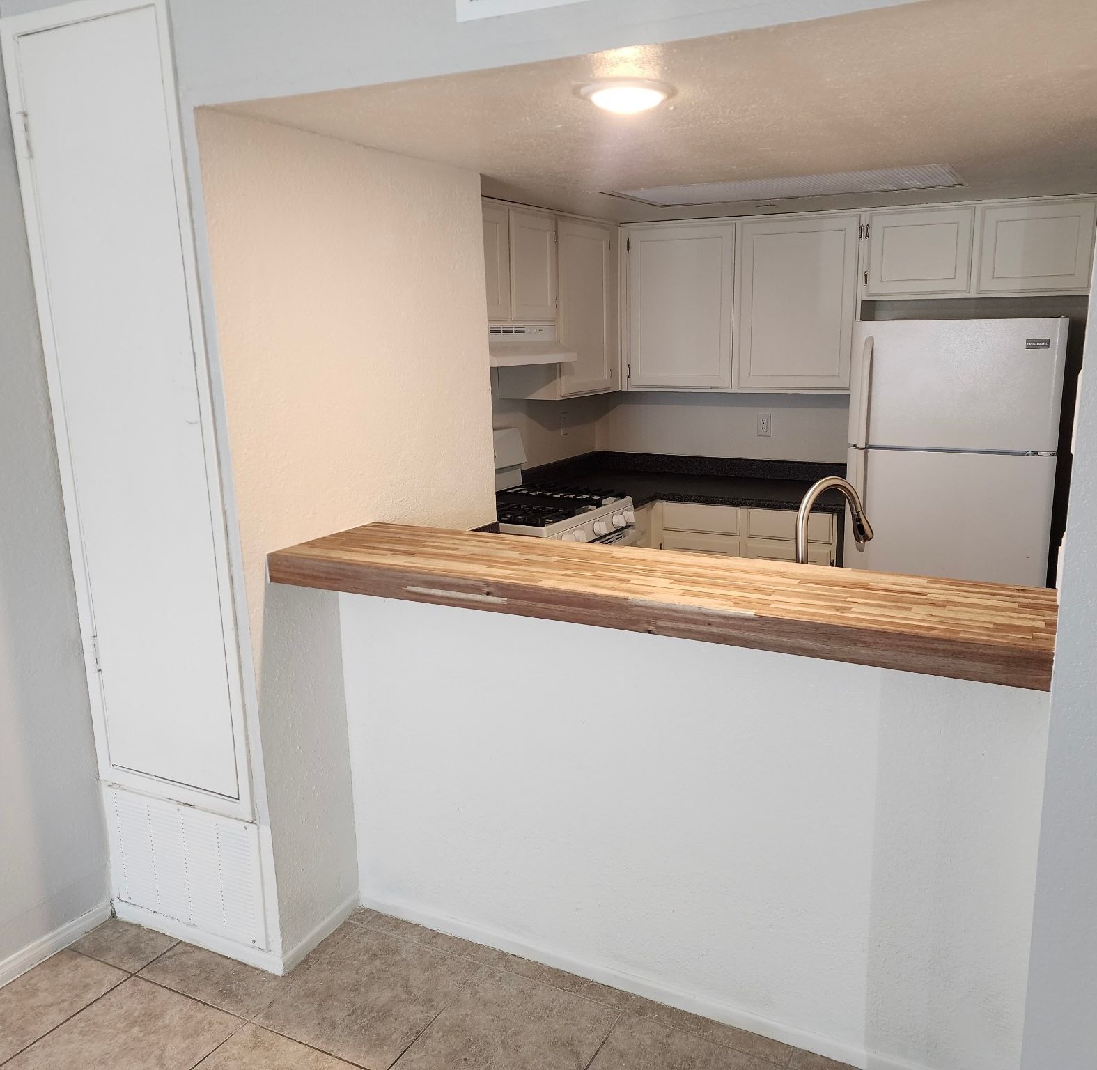 A kitchen with white cabinets and a white refrigerator
