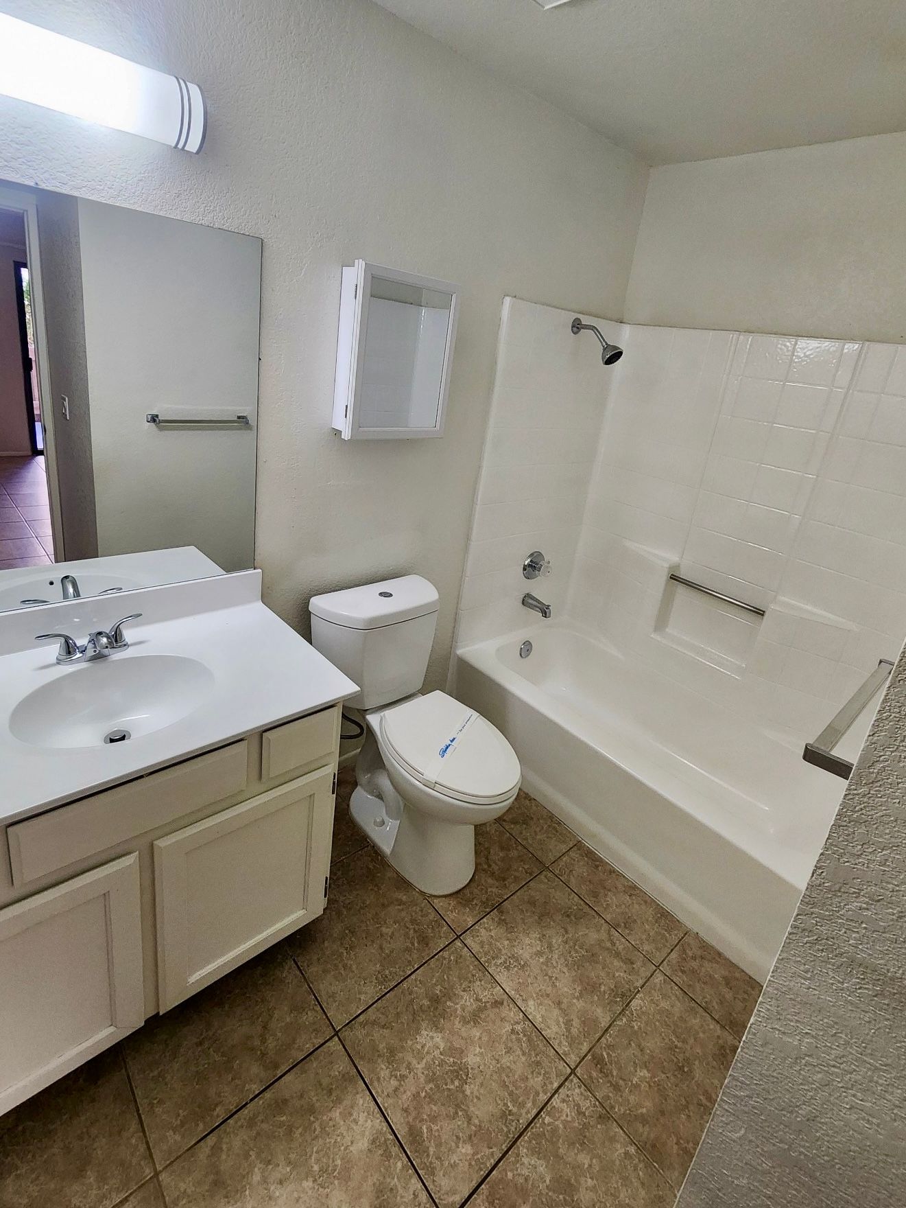 A bathroom with a toilet , sink , bathtub and mirror.