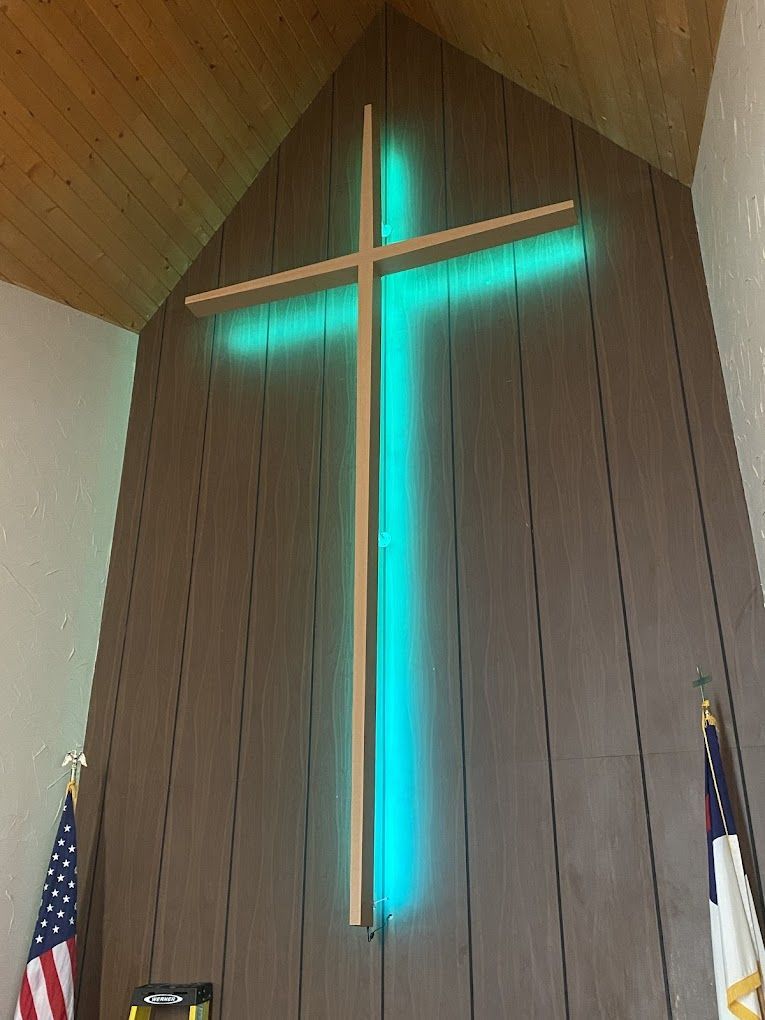 A wooden cross with a blue light behind it in a church.