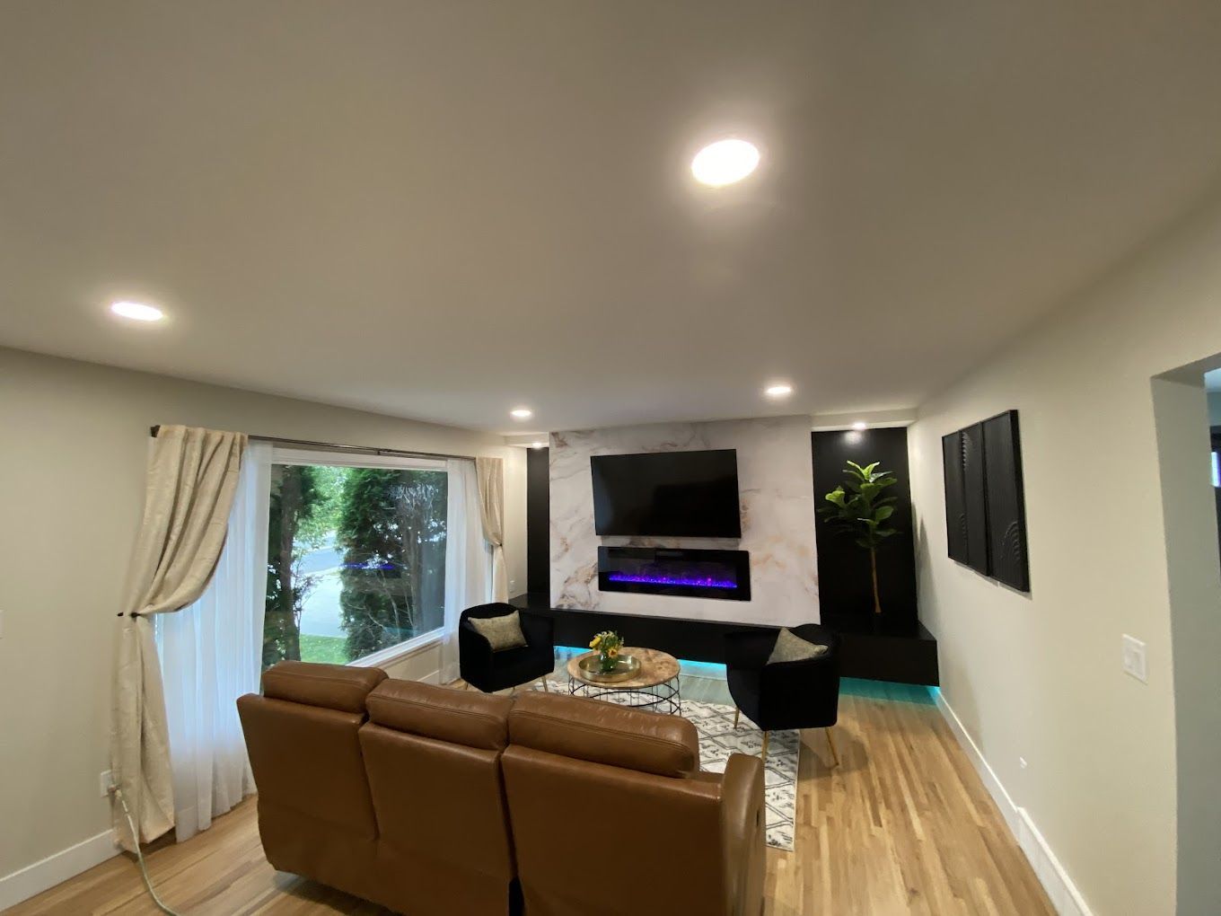 A living room with a couch , chairs , television and fireplace.