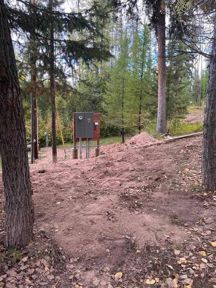 A dirt field in the middle of a forest with trees in the background.