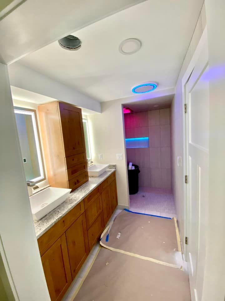 A bathroom with two sinks , a mirror and a walk in shower.