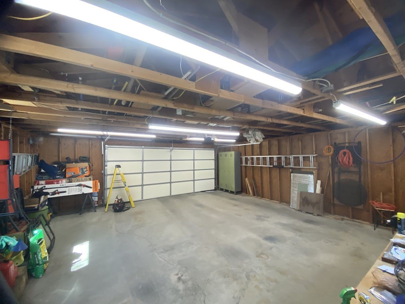 A large empty garage with a garage door and a ladder.