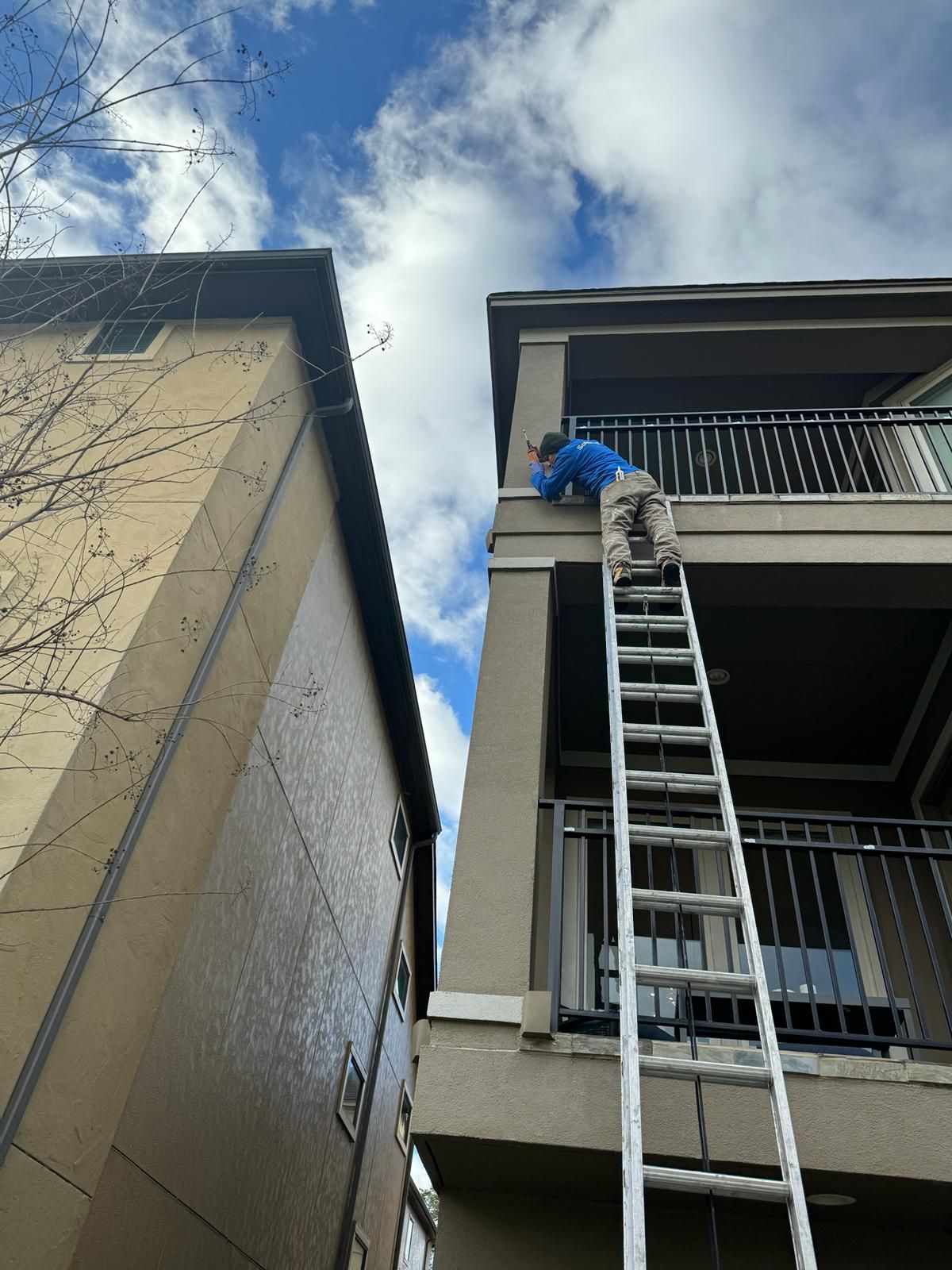 A man is standing on a ladder on the side of a building.