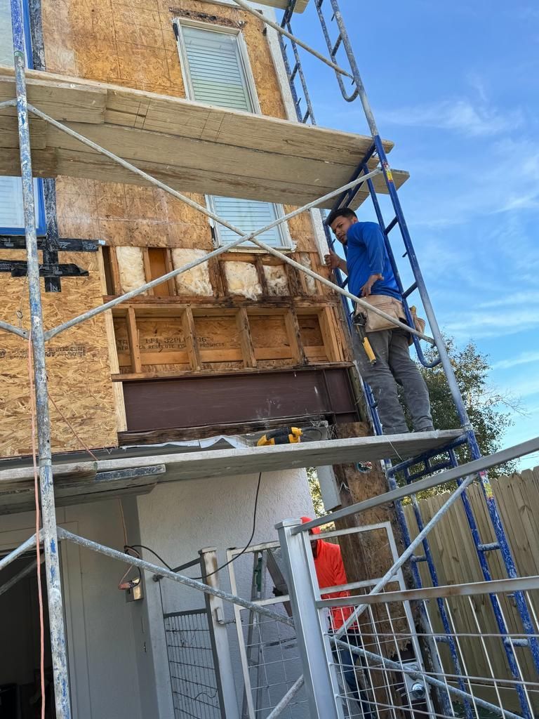 A man is standing on a scaffolding next to a building.
