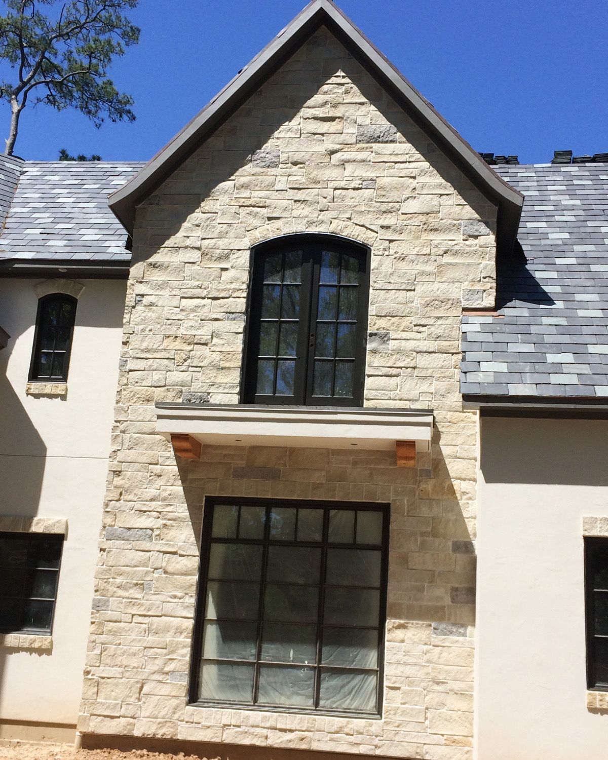 A stone house with a black window and a slate roof