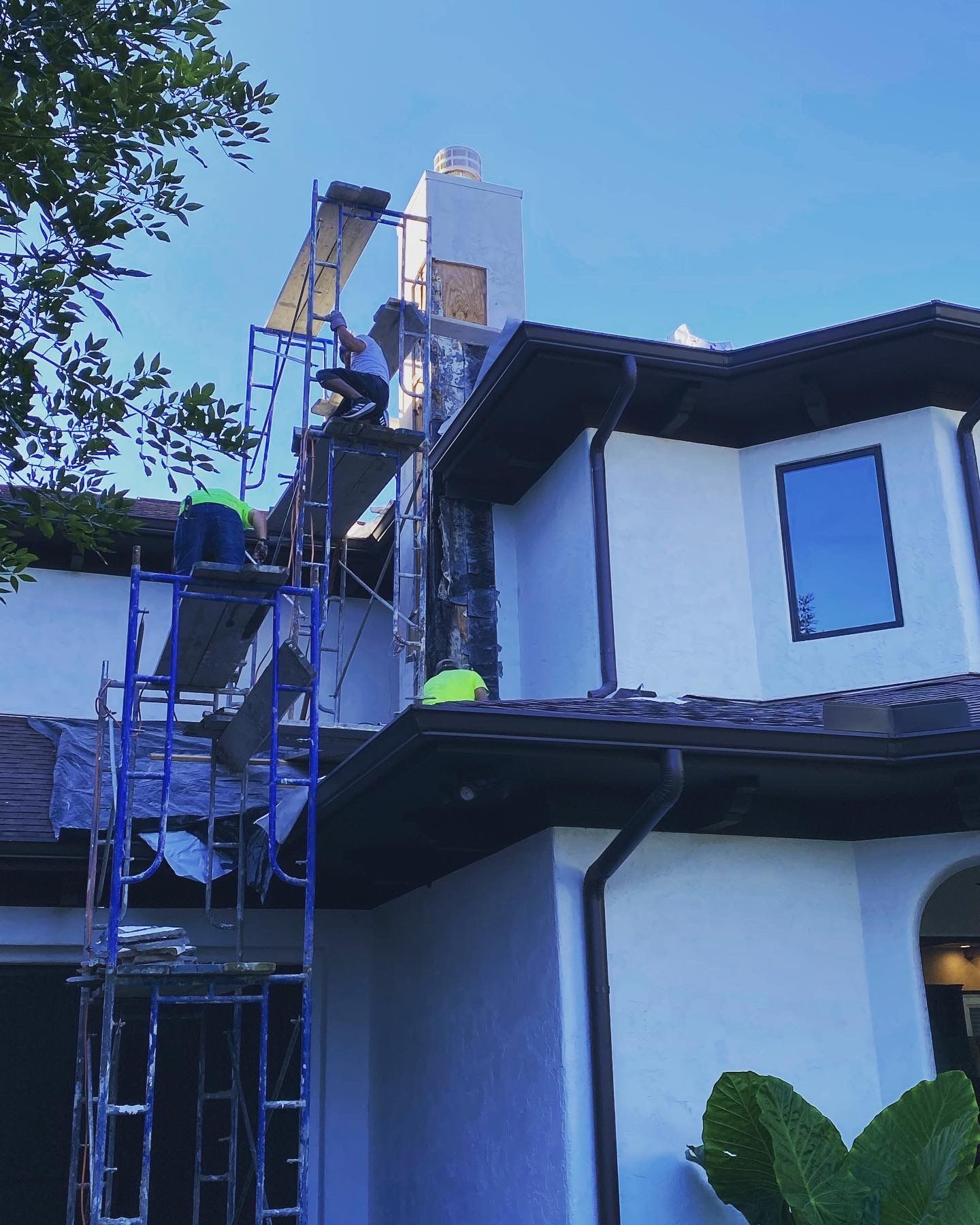 A man is standing on a scaffolding on the side of a house