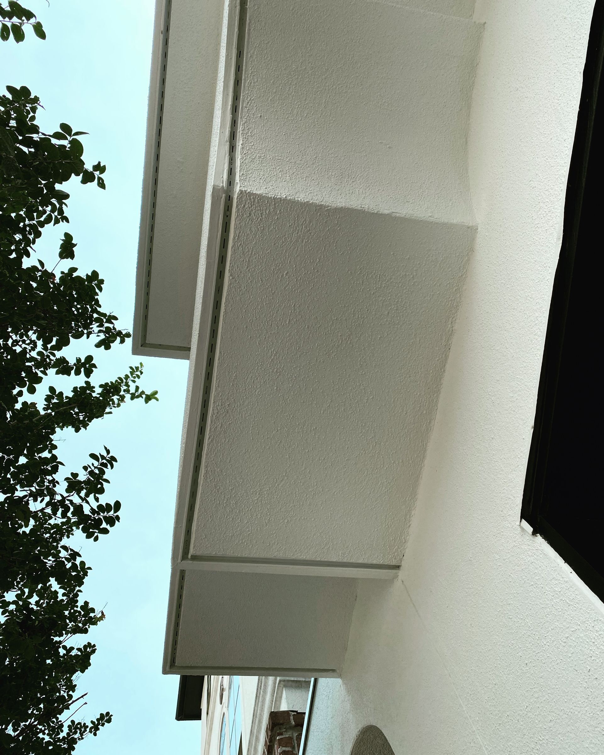 Looking up at a white building with trees in the background