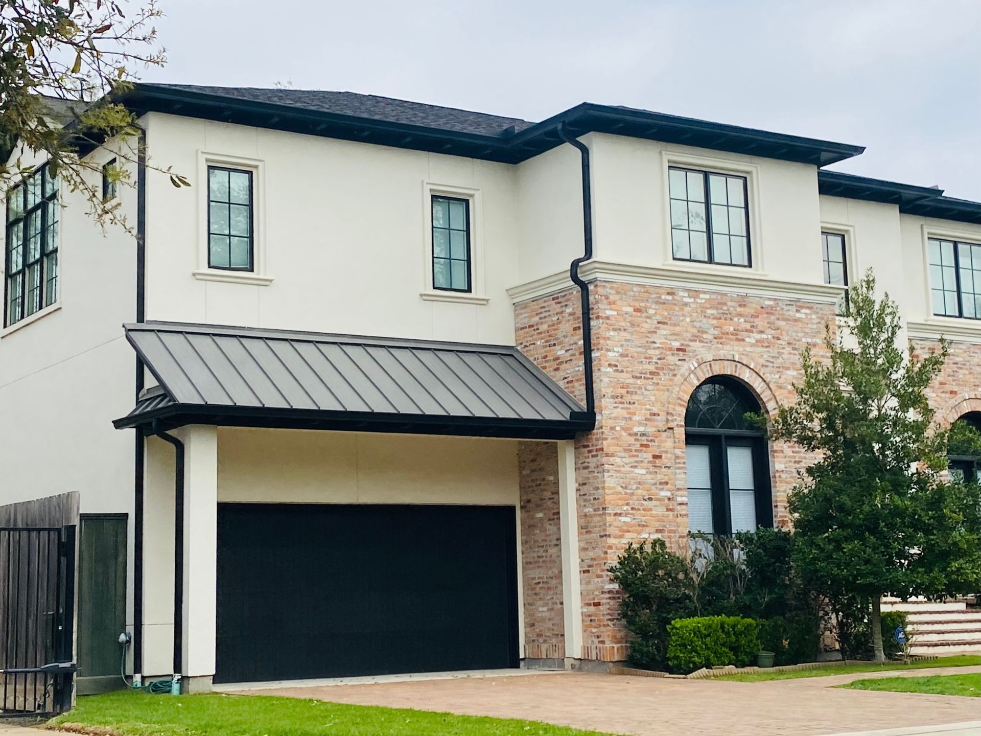 A large white house with a black garage door and a black roof.