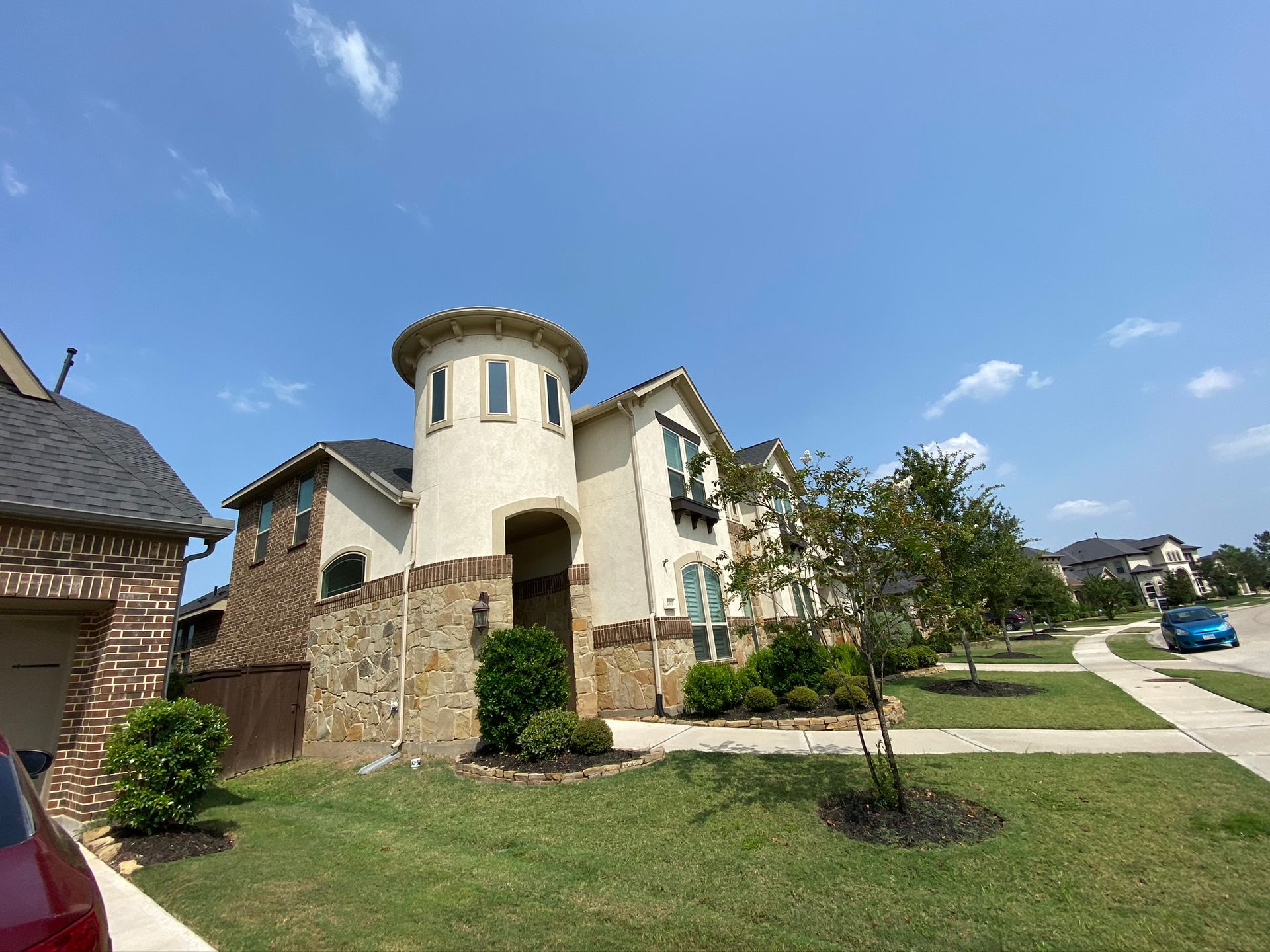 A large white house with a tower on top of it is in a residential neighborhood.