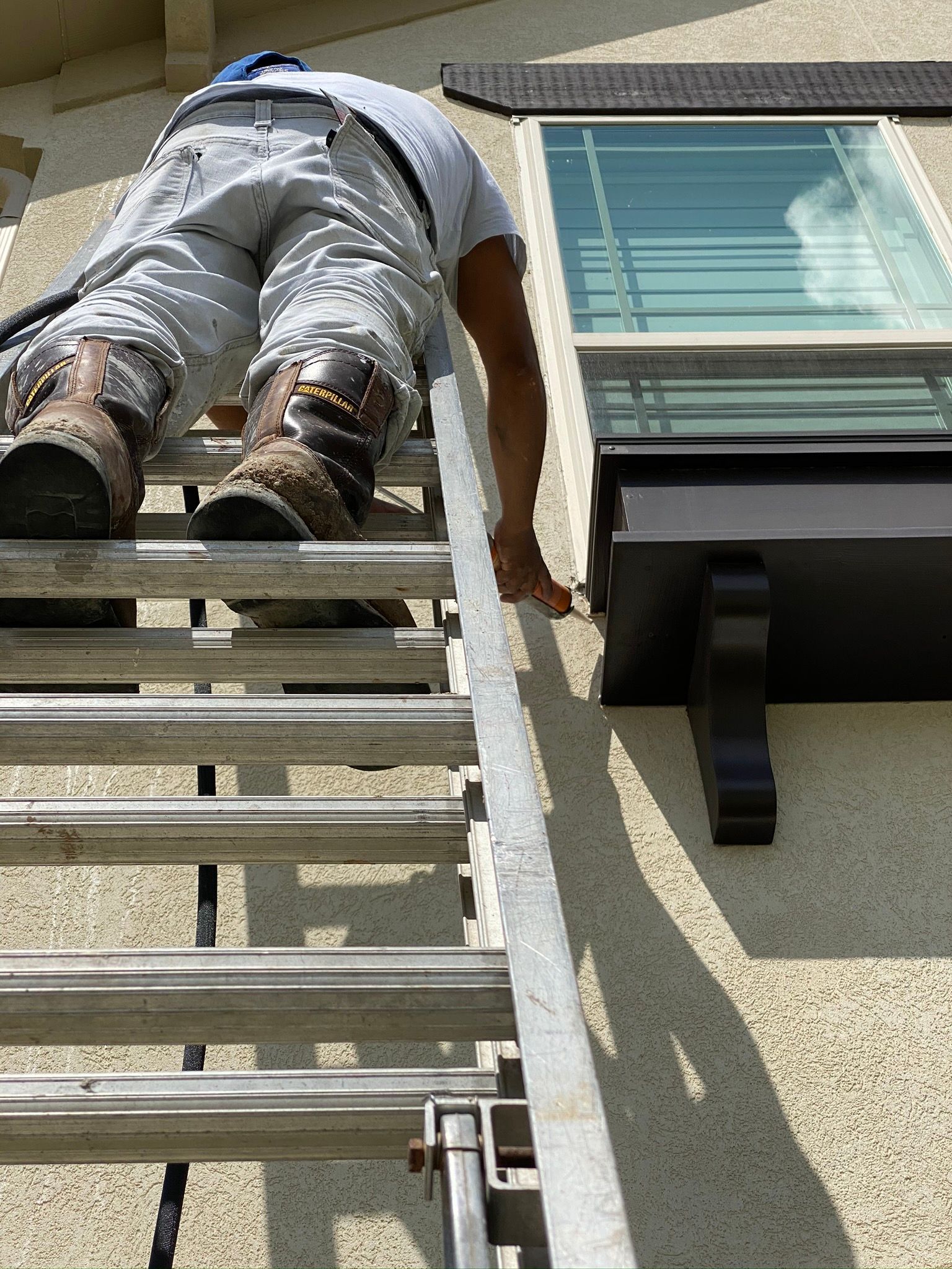 A man is standing on a ladder next to a window.