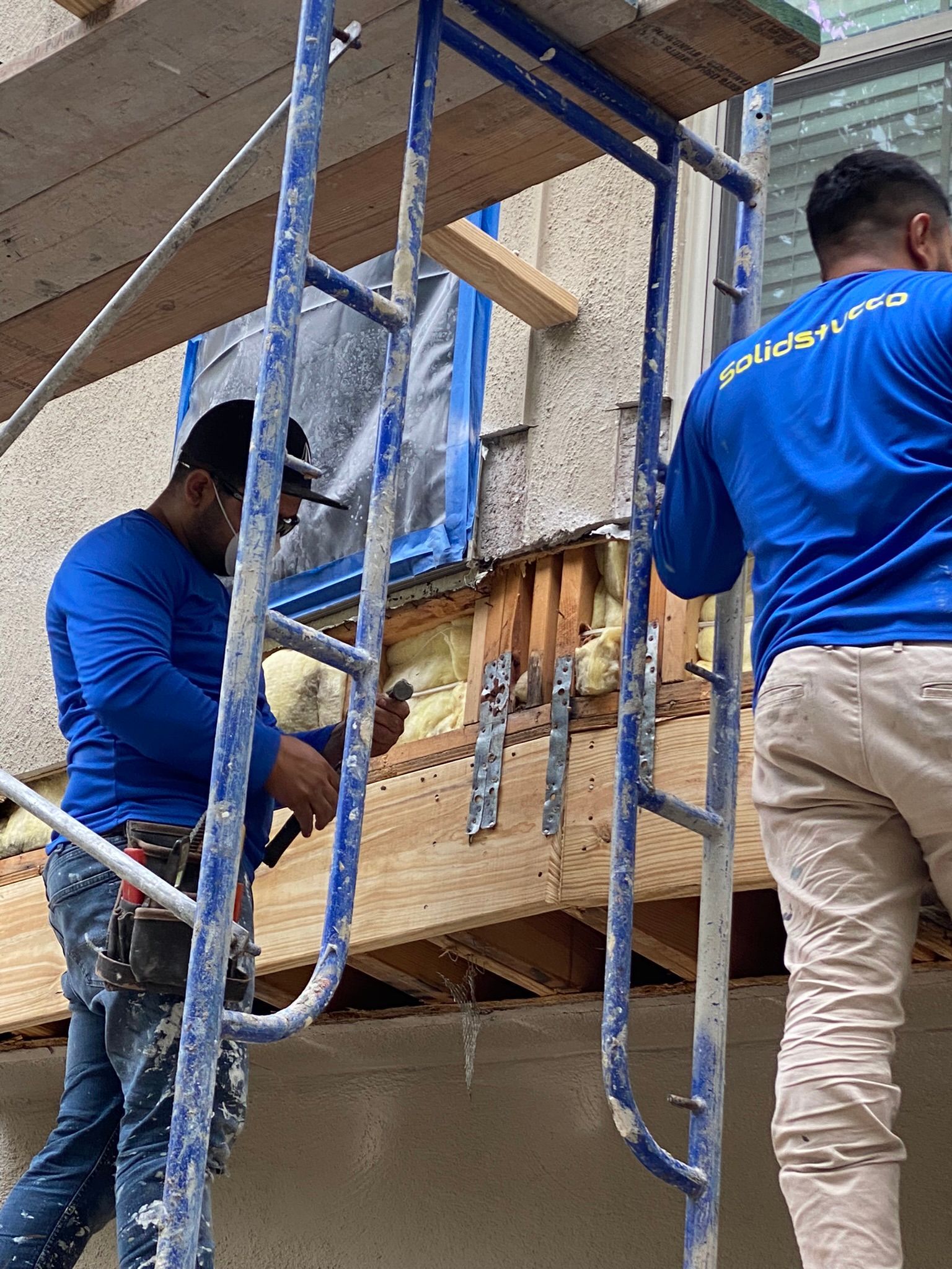 Two men are working on a building on a scaffolding.