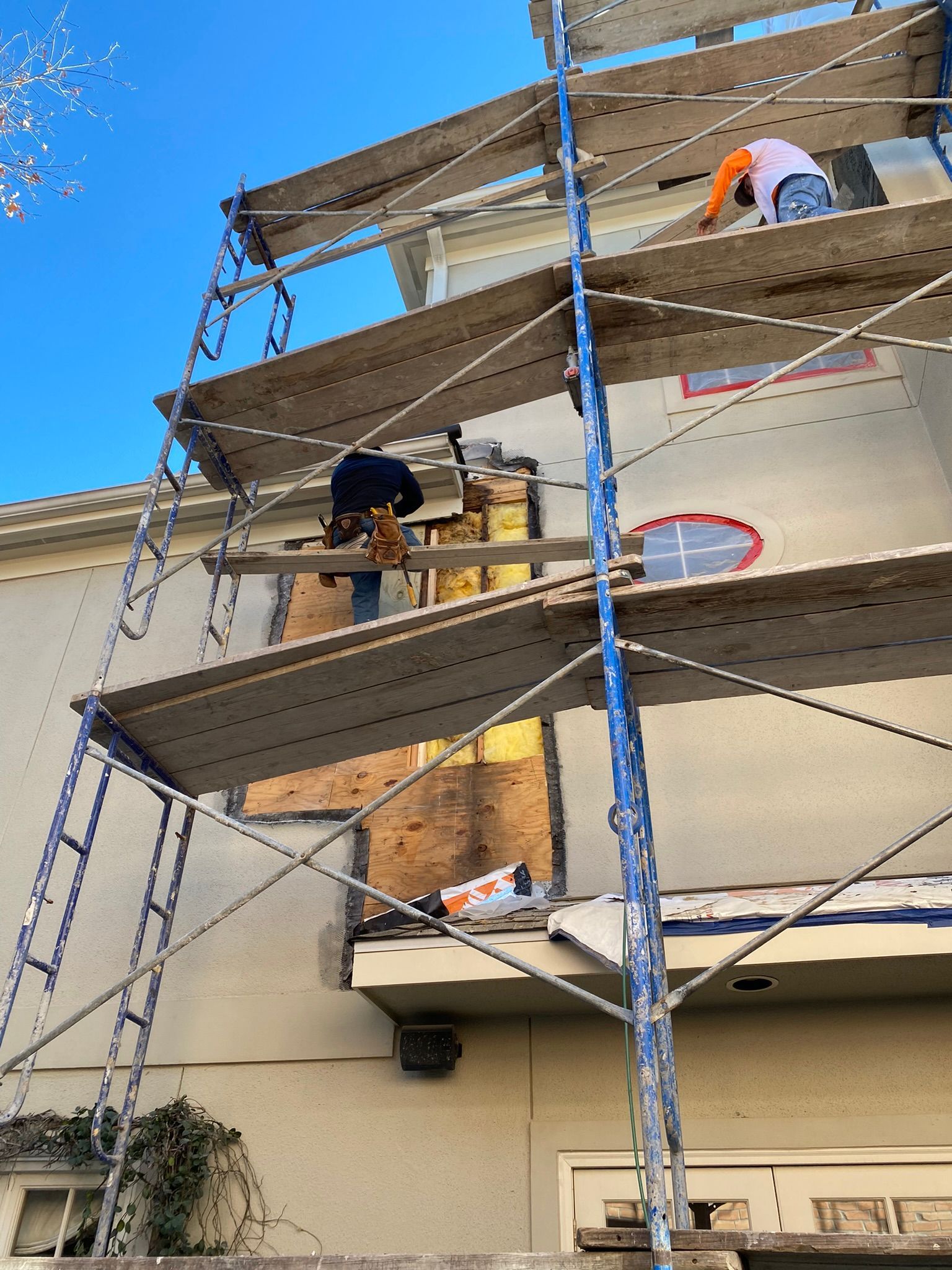A man is standing on a scaffolding on the side of a building.