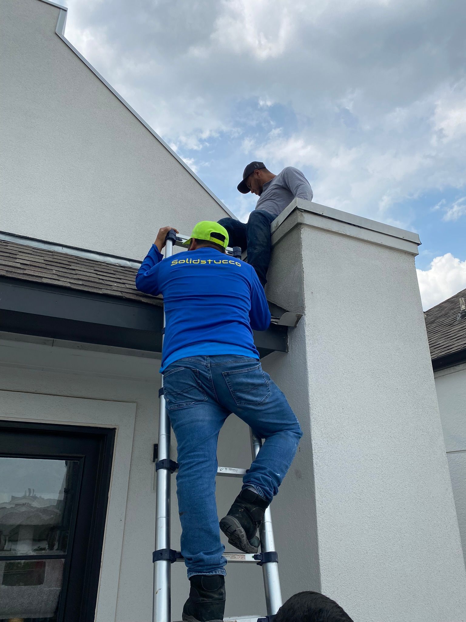 A man is standing on a ladder on the side of a building.