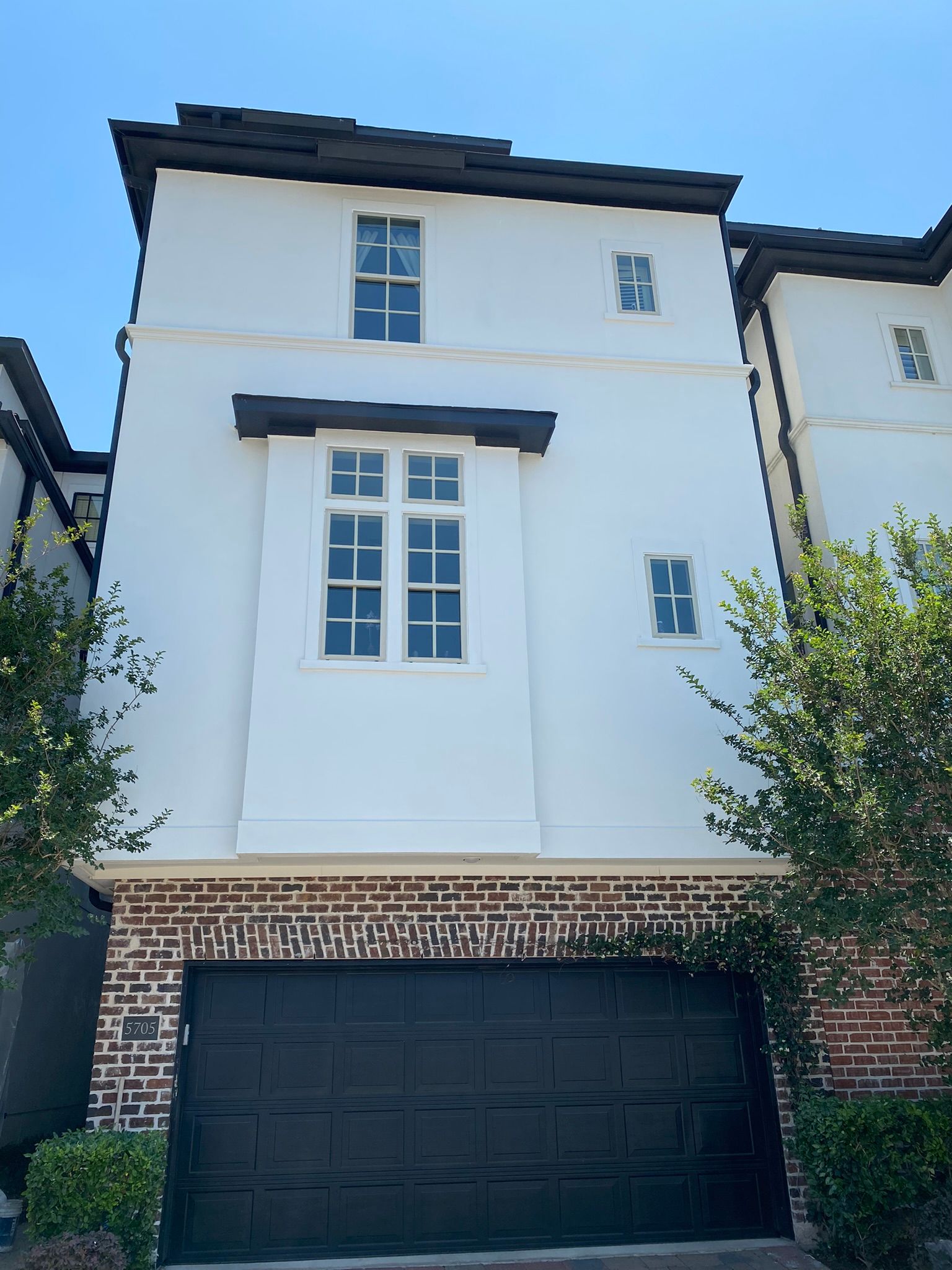 The front of a white house with a black garage door.