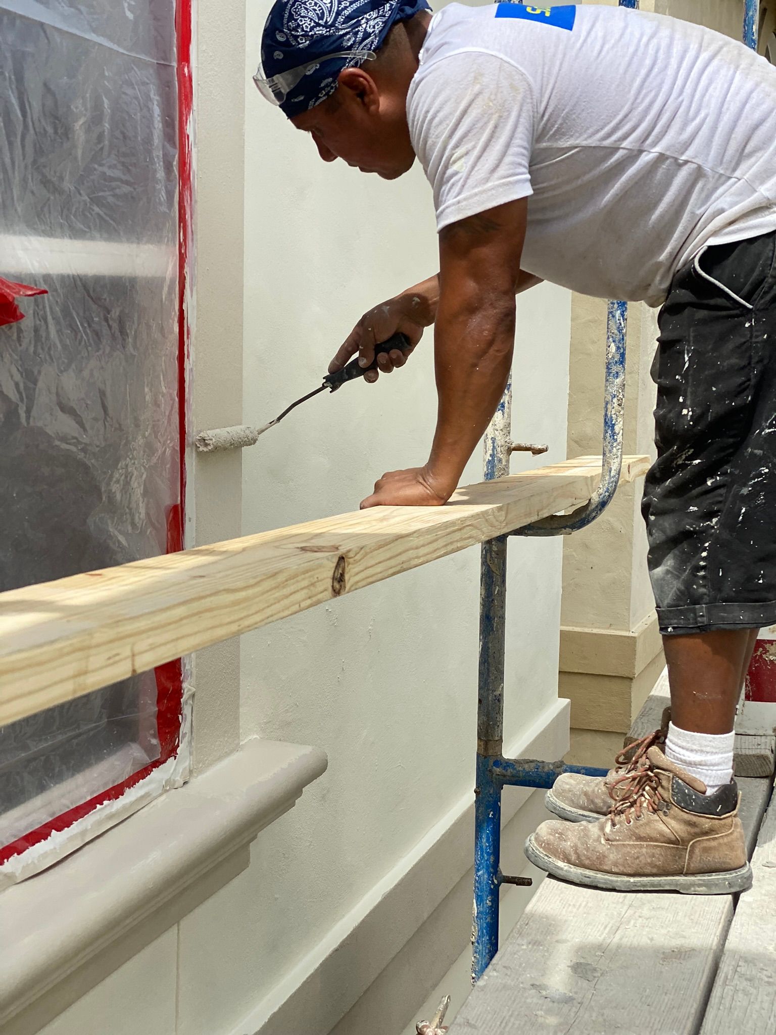 A man is standing on a scaffolding painting a wall.