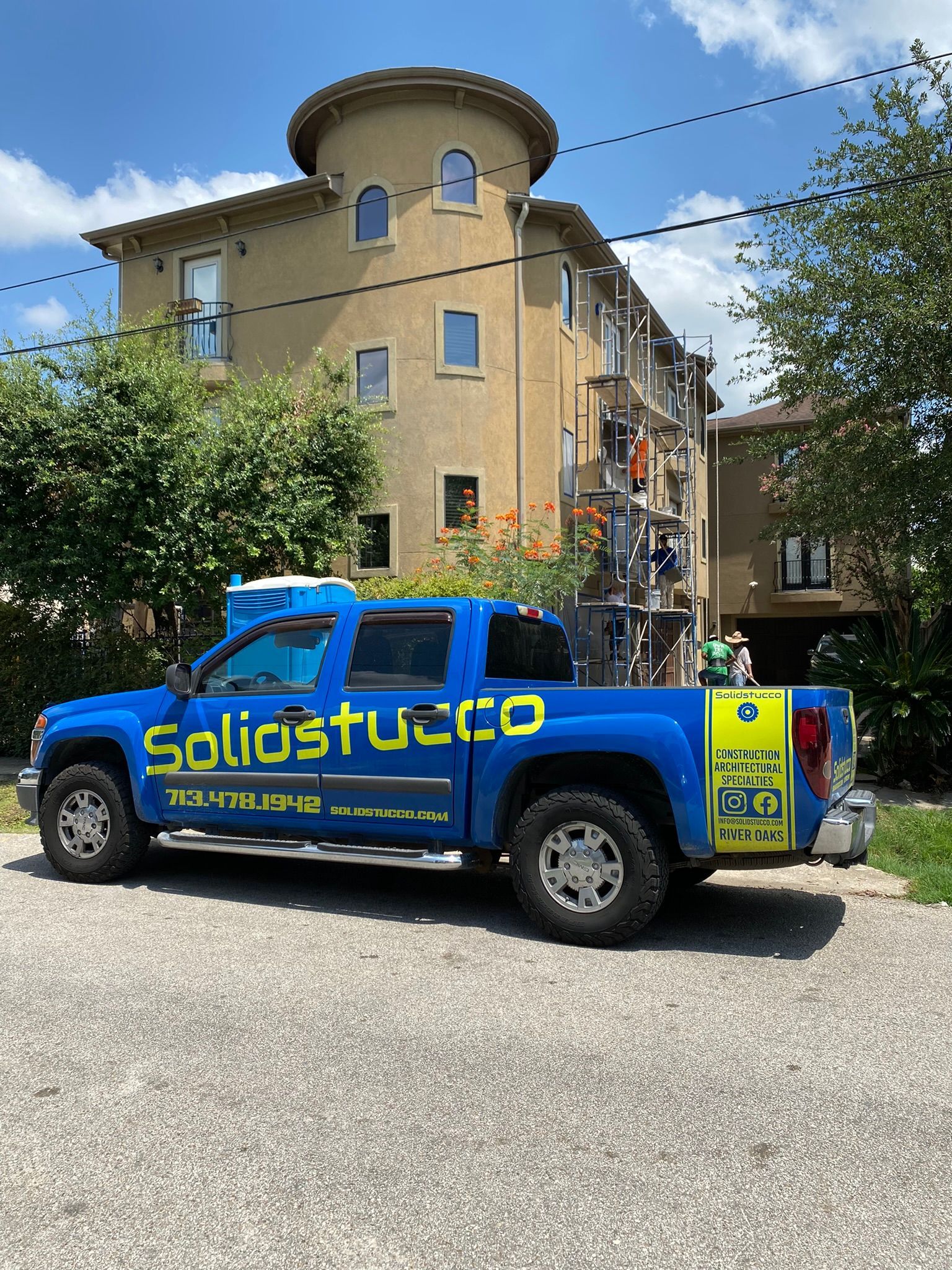 A blue truck is parked in front of a building.
