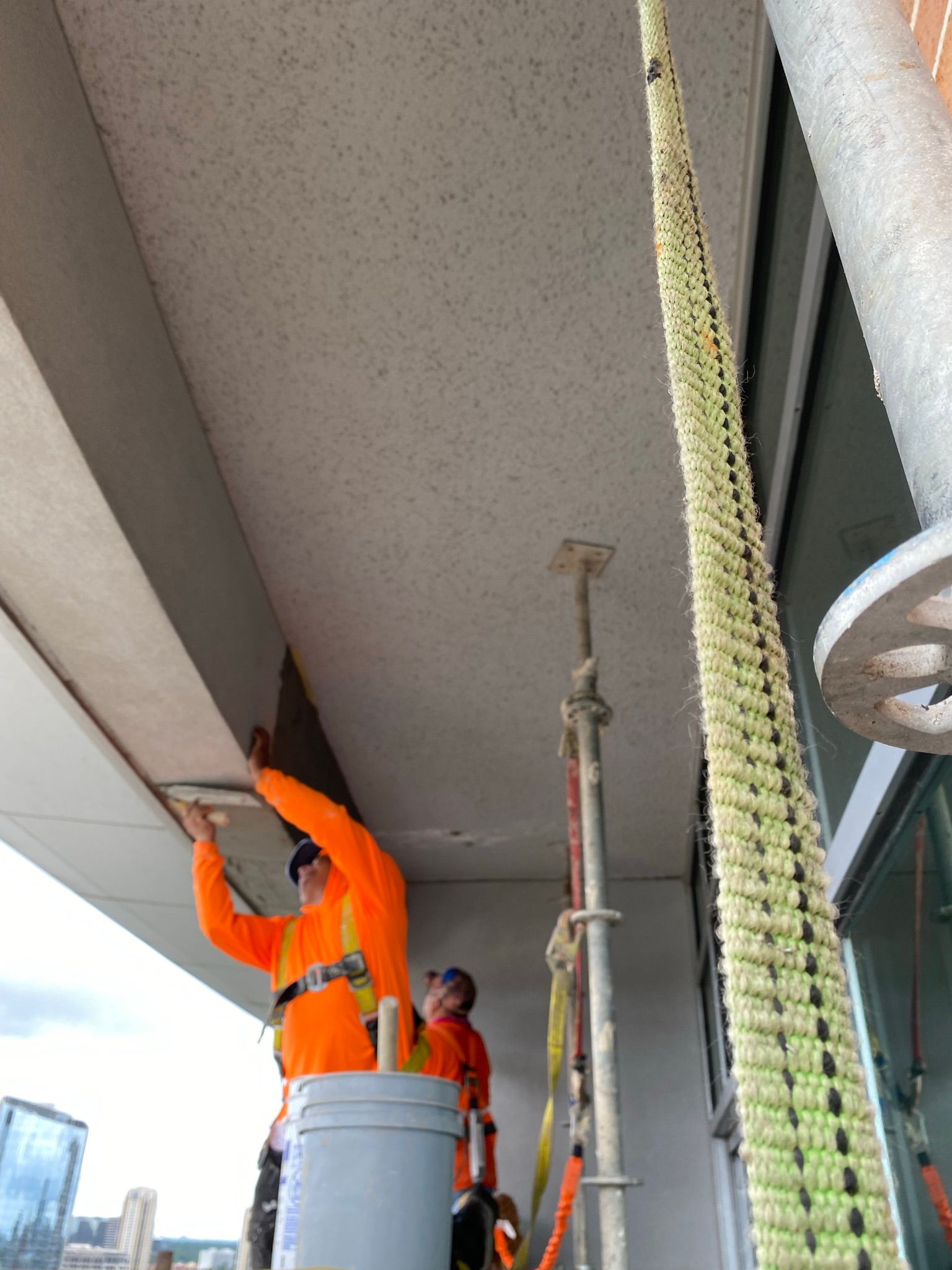 Two construction workers are working on the ceiling of a building