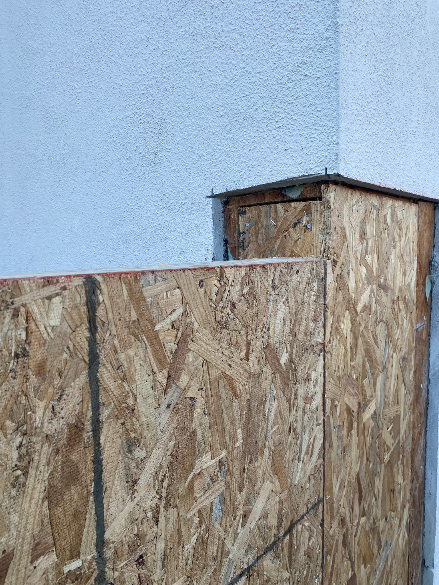 A close up of a wooden fence against a white wall.