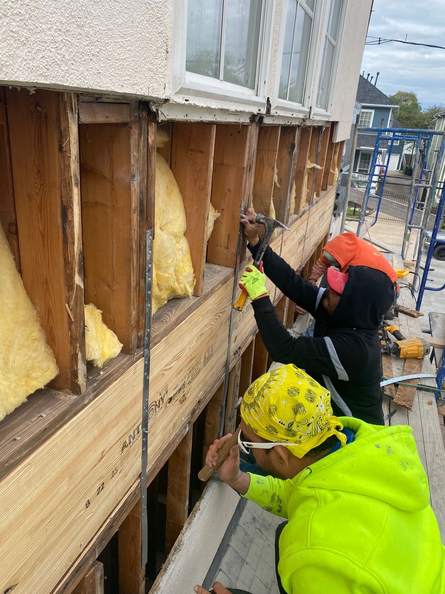 Two men are working on the side of a building.
