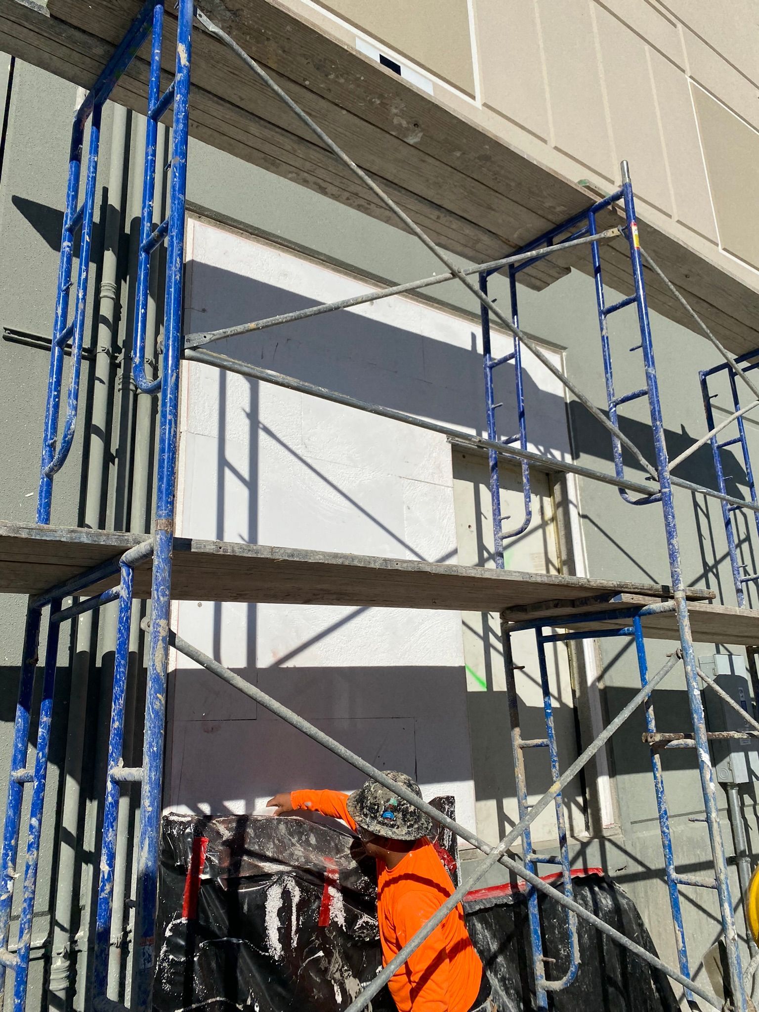 A man is painting a building with scaffolding in front of it
