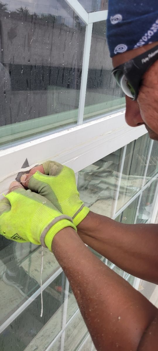A man wearing yellow gloves is working on a window.