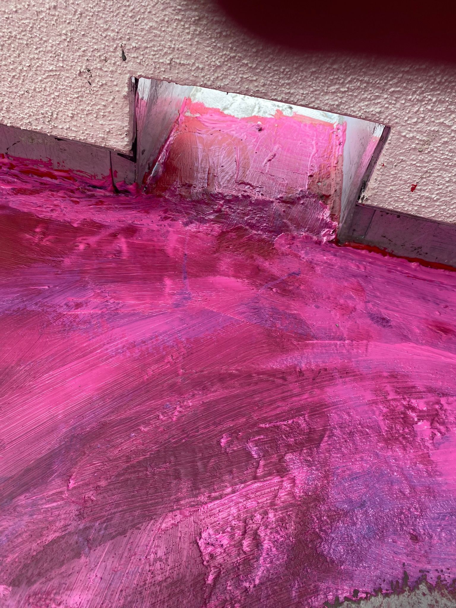 A spatula is being used to remove pink paint from the ground.