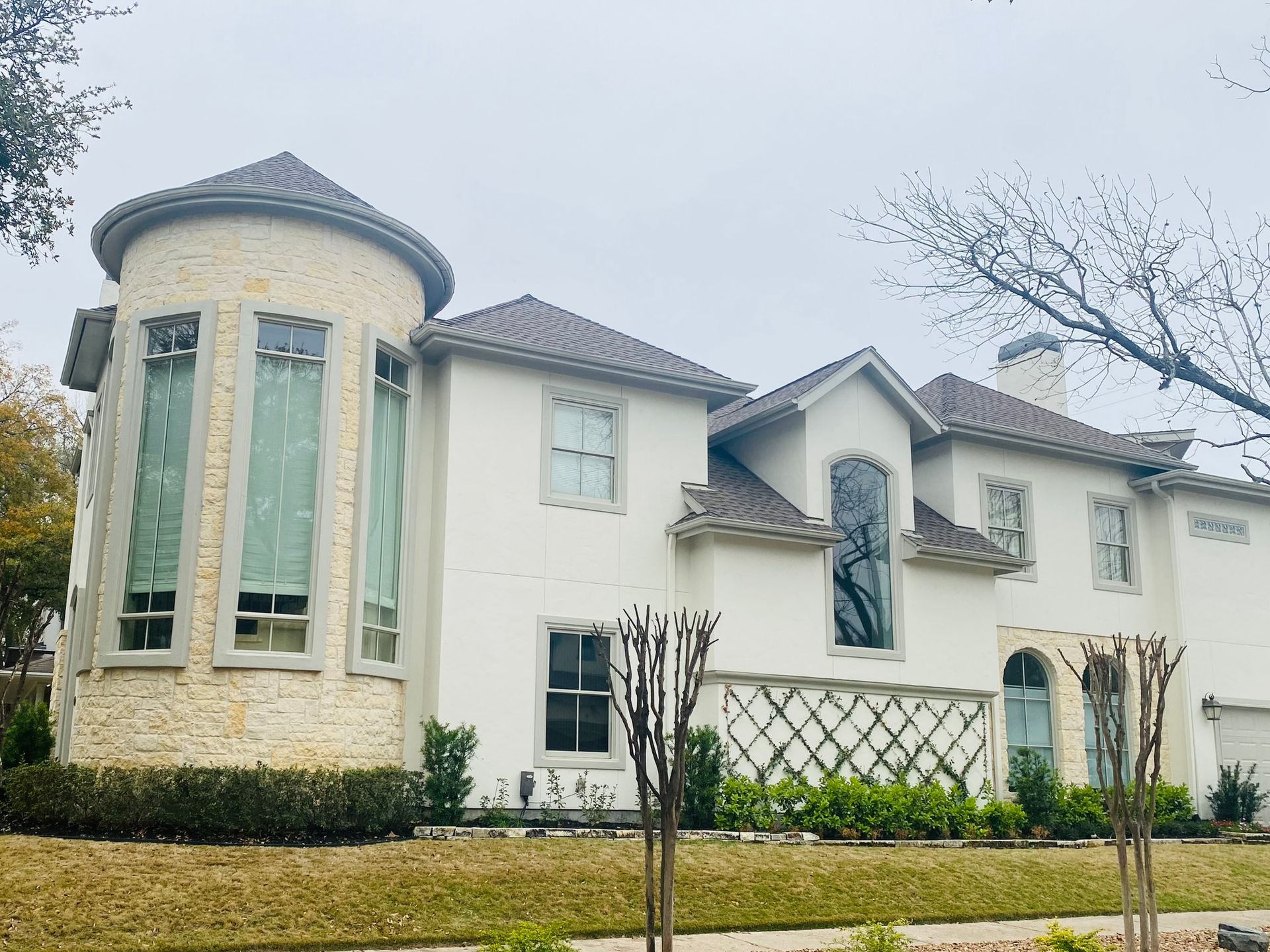 A large white house with a brown roof is sitting on top of a lush green lawn.