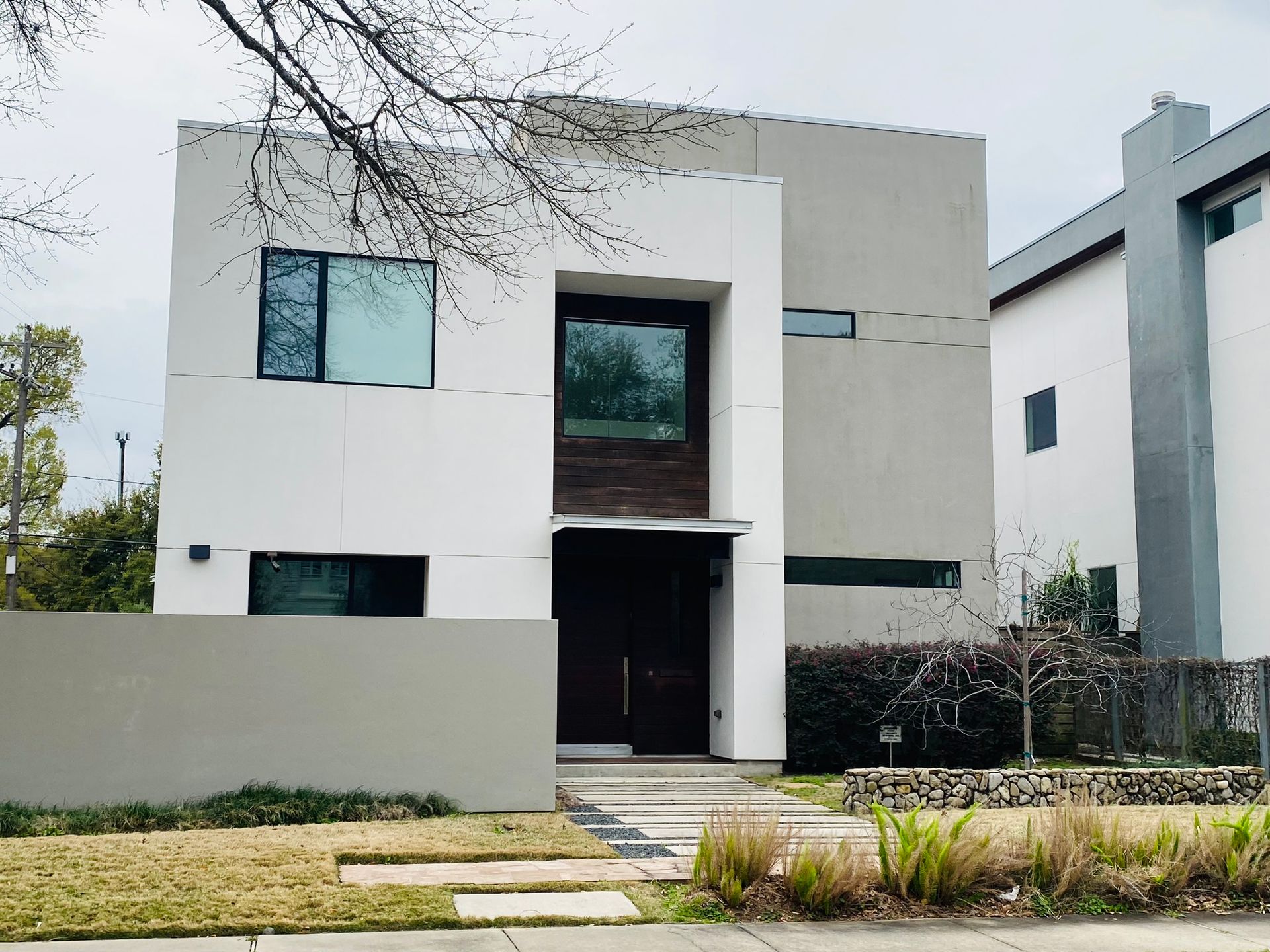 A modern house with a large window and a fence in front of it.