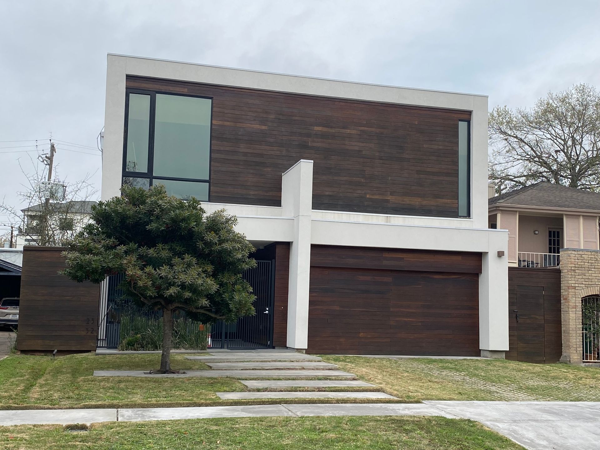 A modern house with a large garage and a tree in front of it.