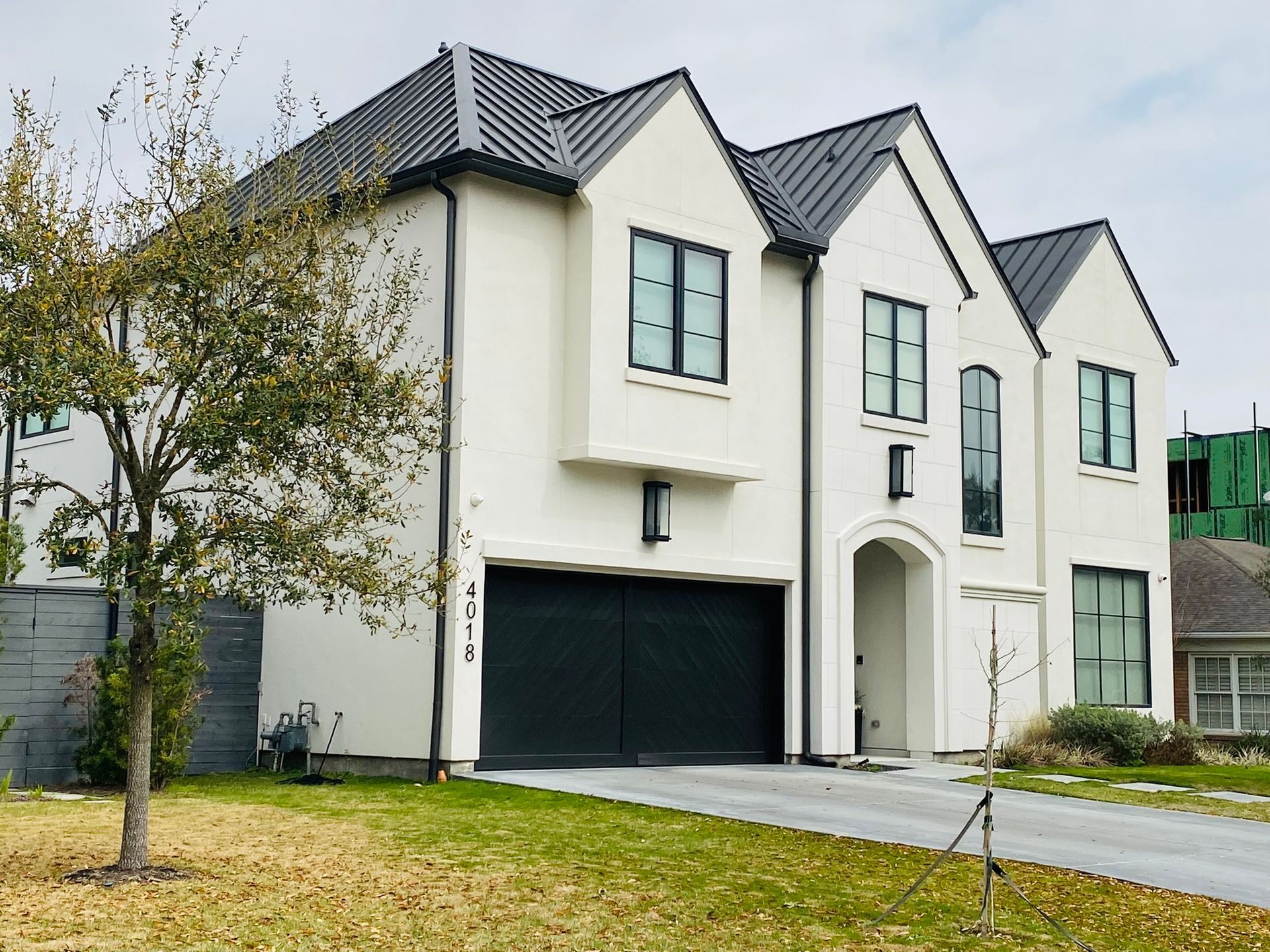 A large white house with a black garage door and a black roof.