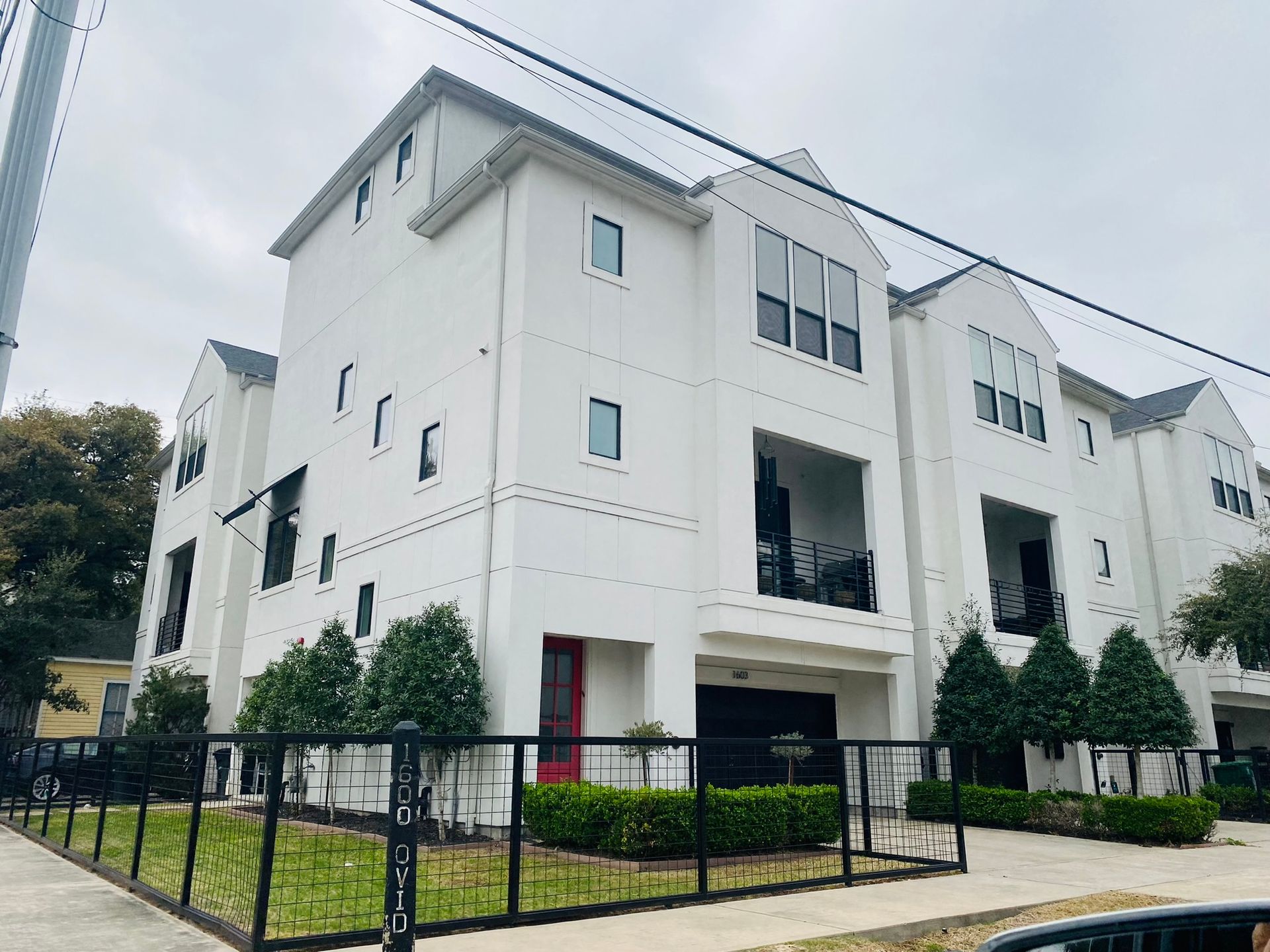 A large white apartment building with a black fence around it.