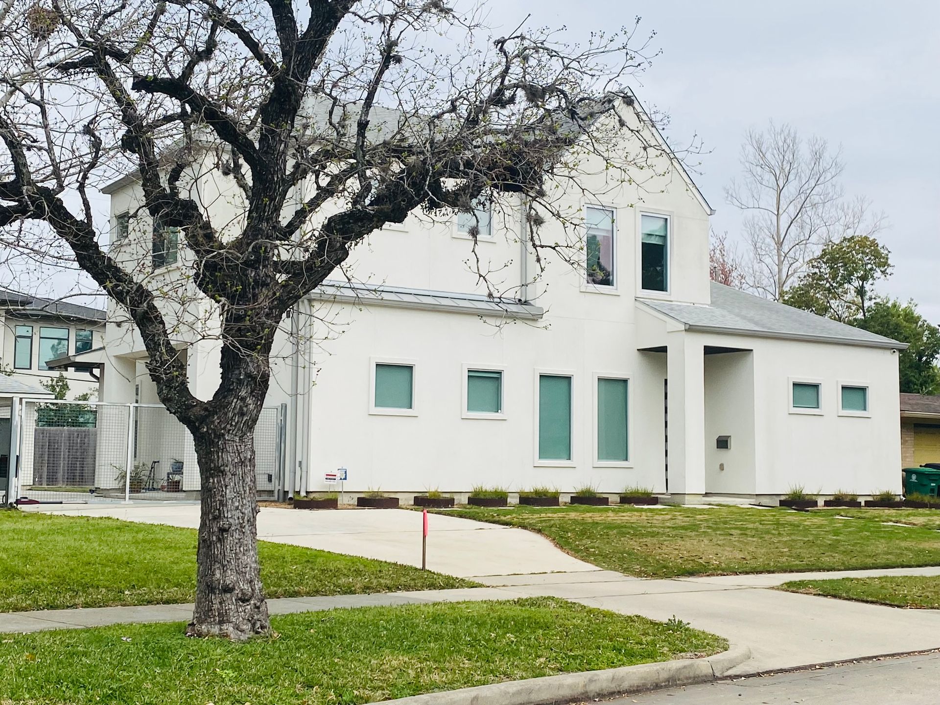 A white house with a tree in front of it.