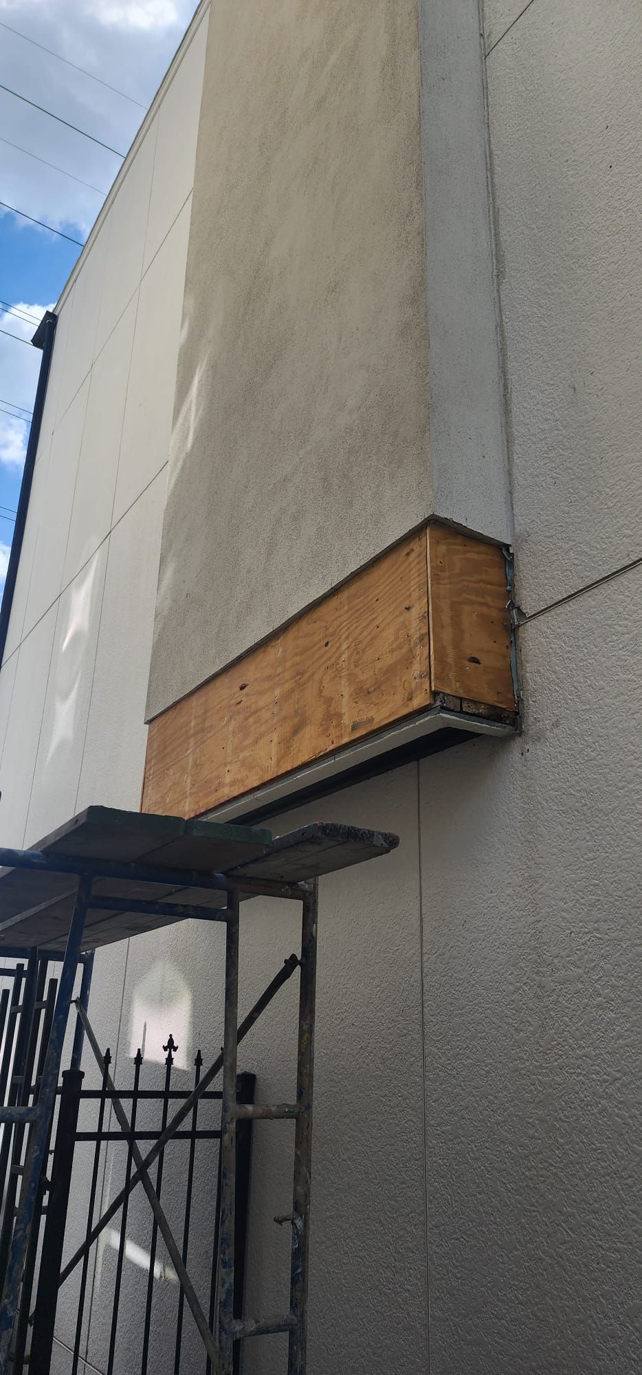 A white building with a wooden box on the side of it.