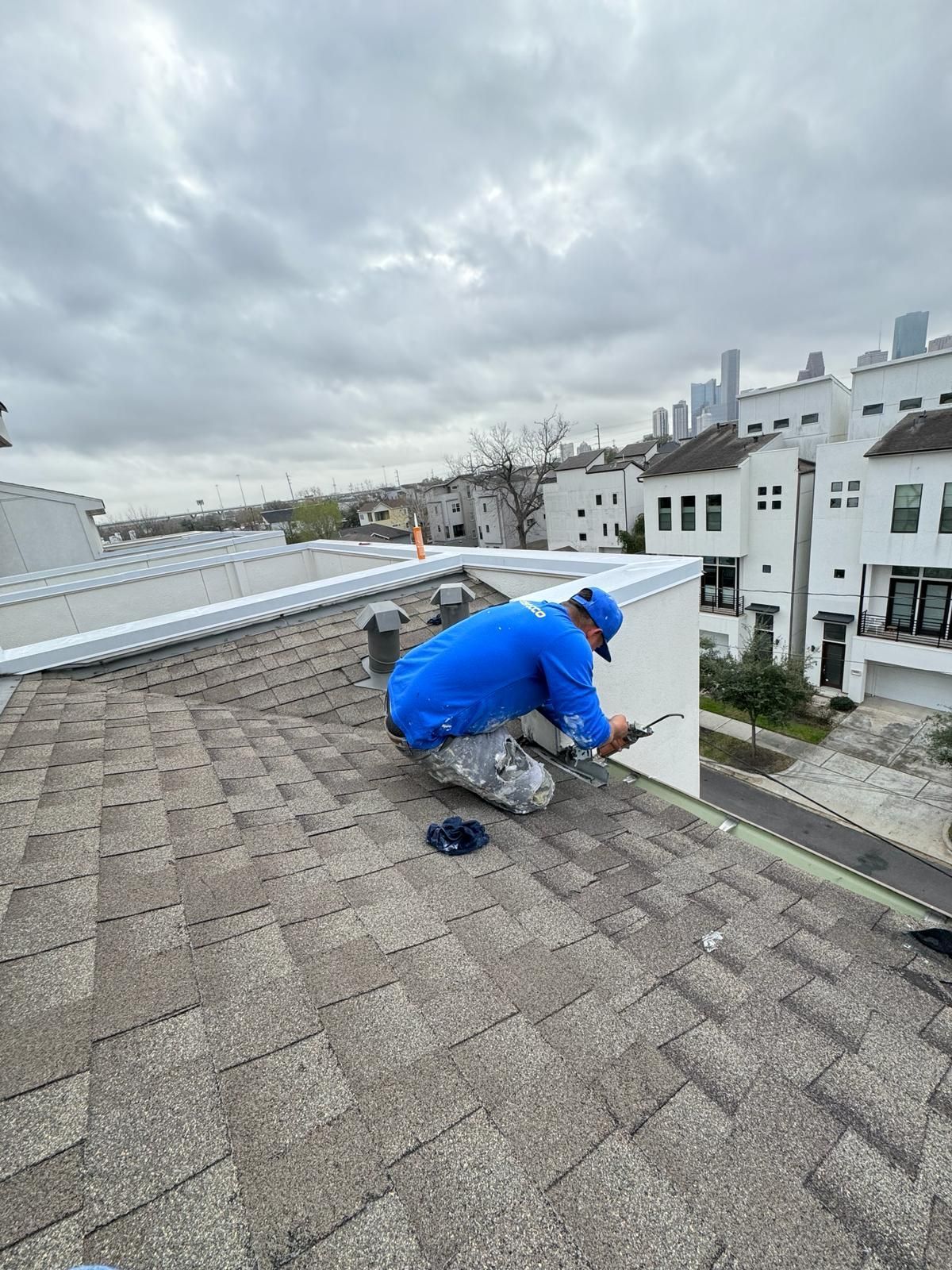 A man is kneeling on the roof of a building.