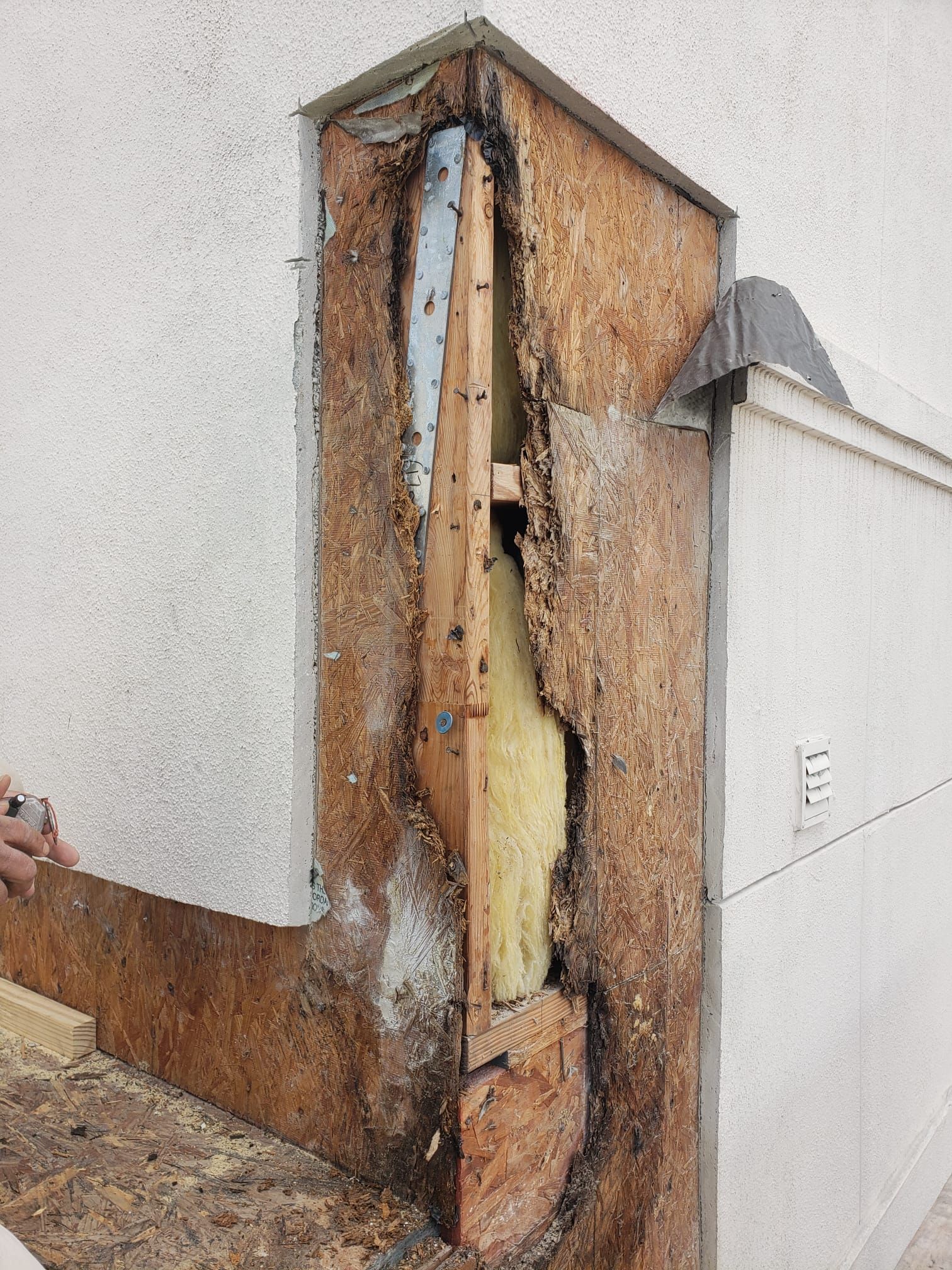 A person is standing next to a wall with a hole in it.