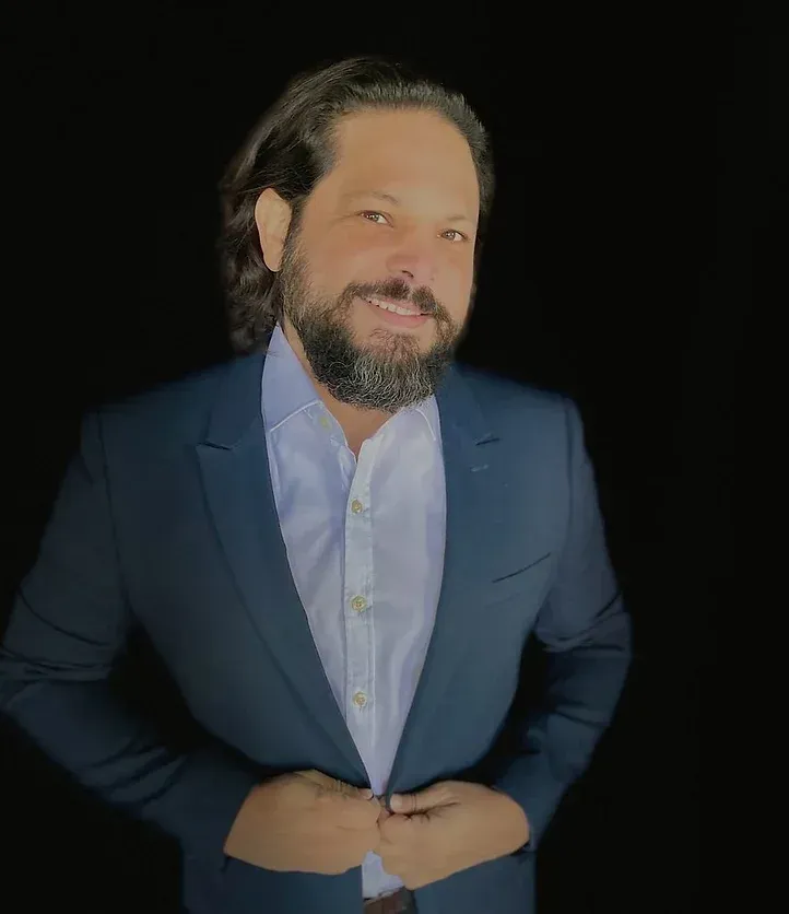 a man with a beard is wearing a blue suit and white shirt .