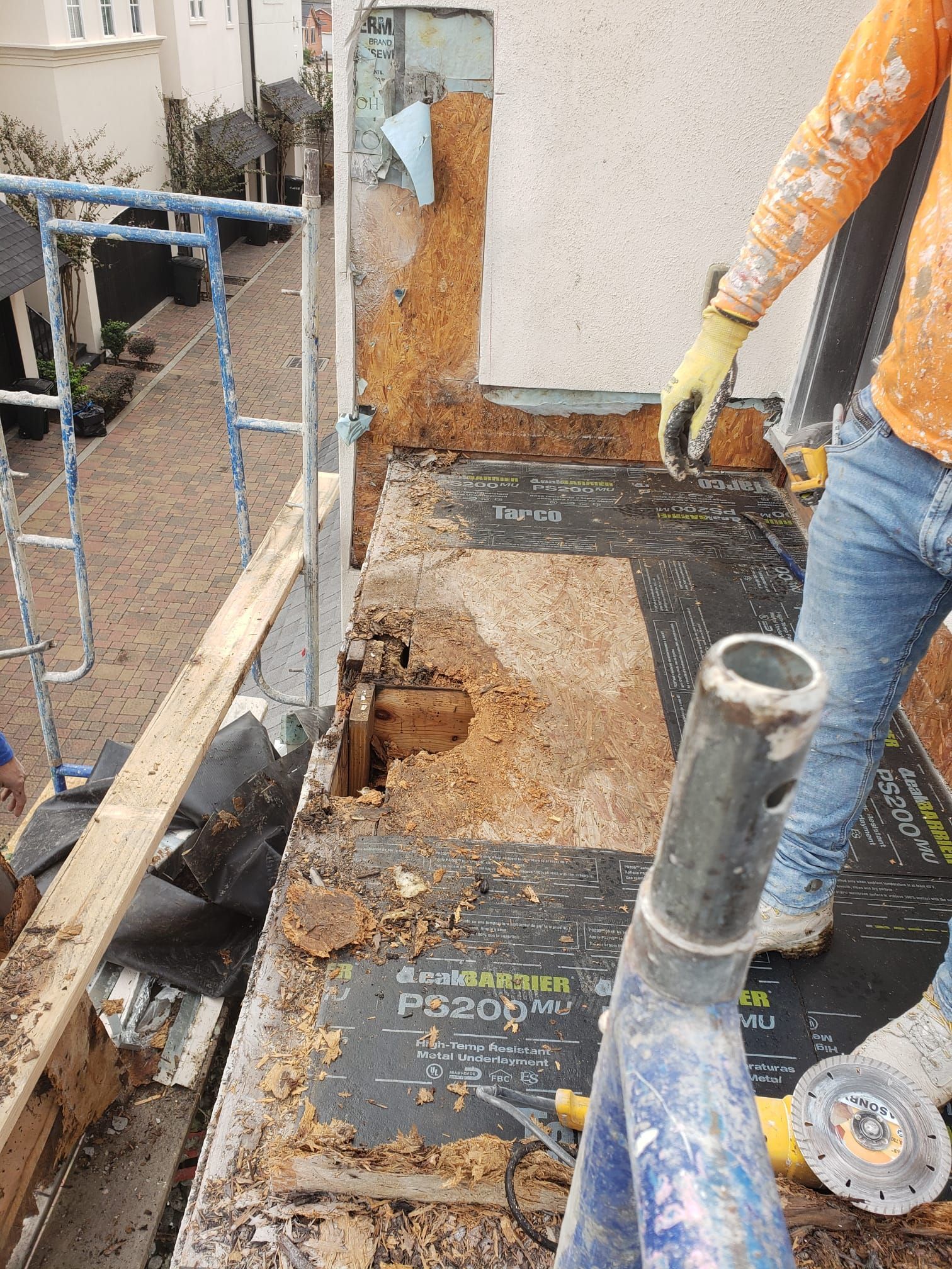 A man is standing on a scaffolding next to a hole in a wall.