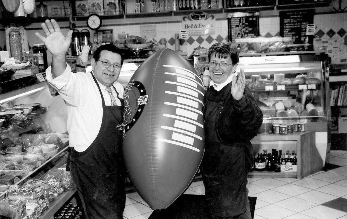 Two men holding a large inflatable football in a store