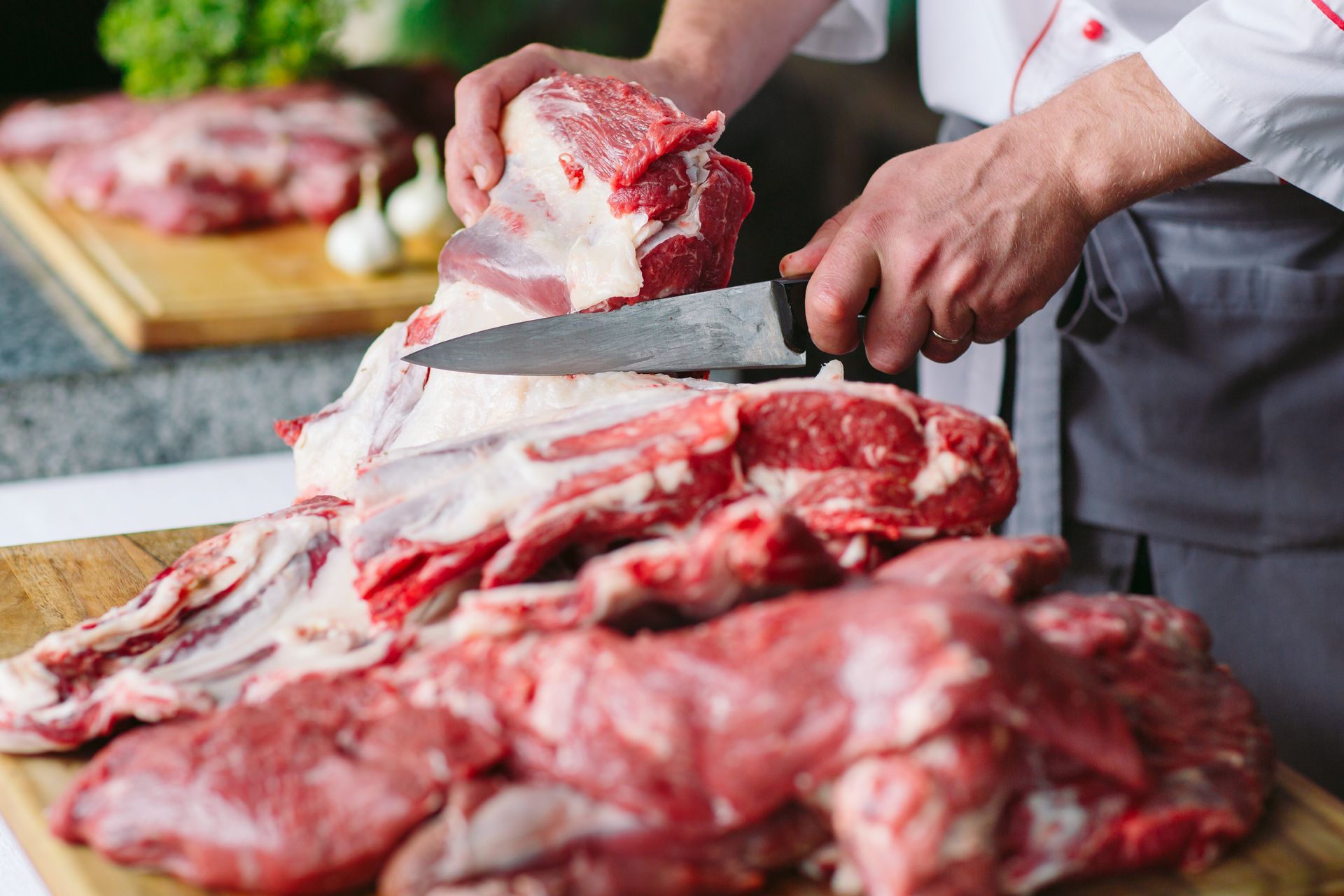 A man is cutting a piece of meat on a cutting board.