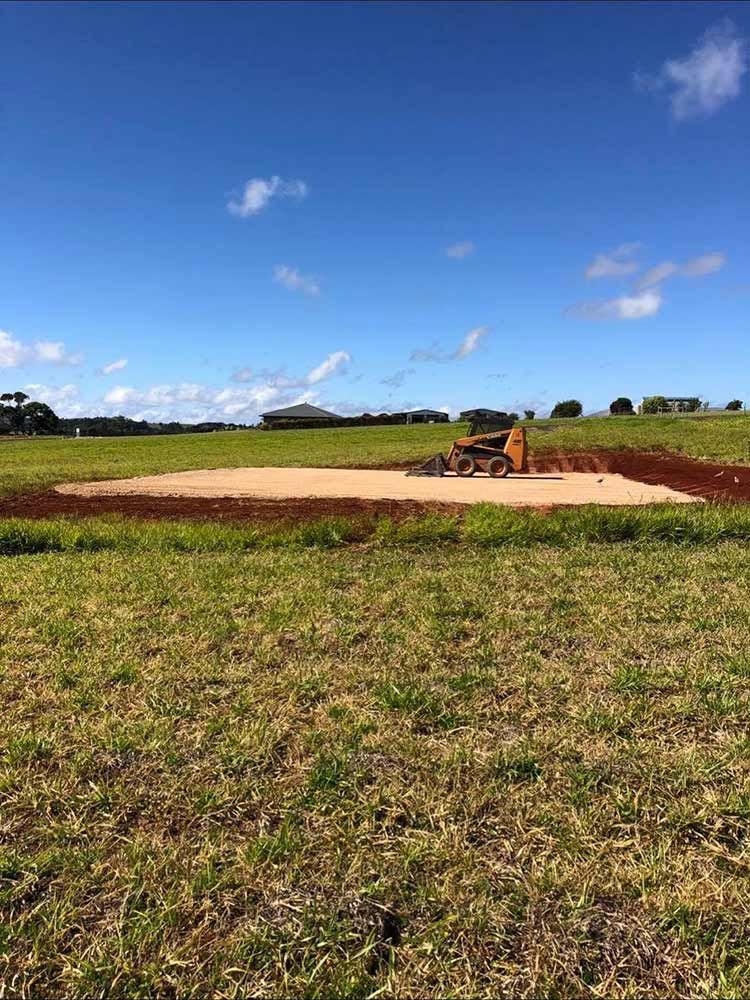 A Bulldozer is Sitting in the Middle of a Grassy Field — Blue Gum Earthworks in Tablelands, QLD