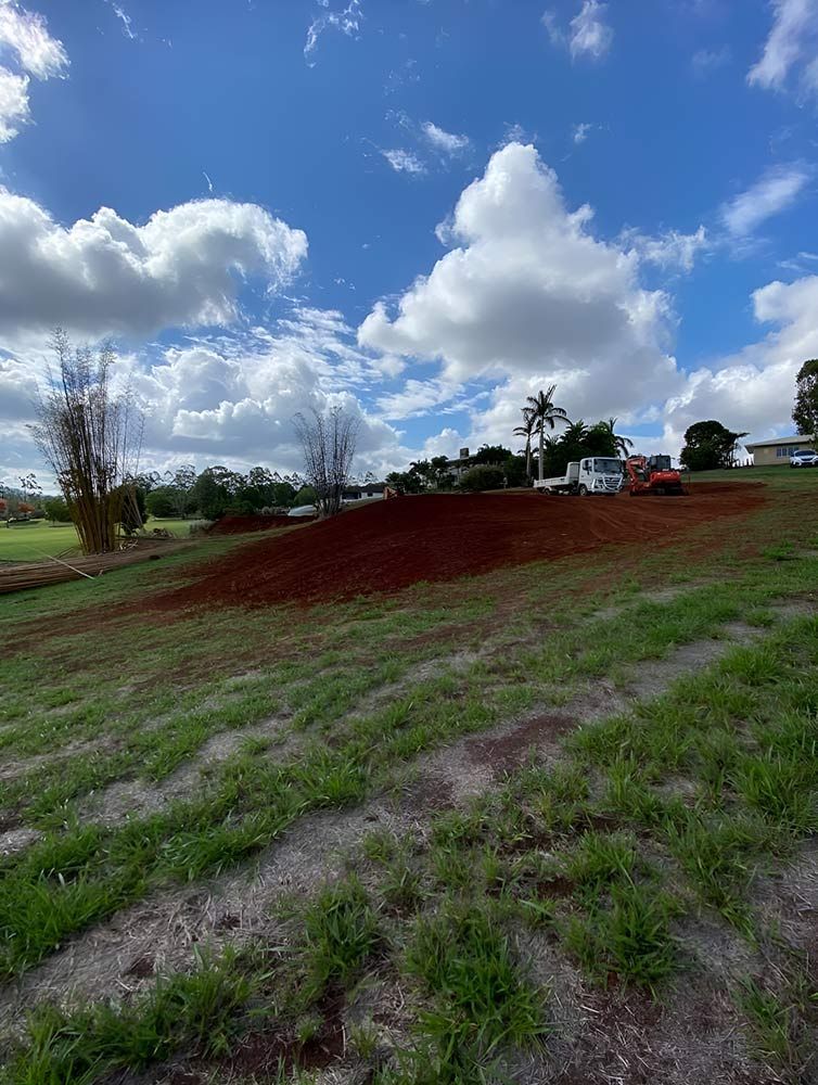 A Large Grassy Field With a Blue Sky and Clouds in the Background — Blue Gum Earthworks in Cairns, QLD