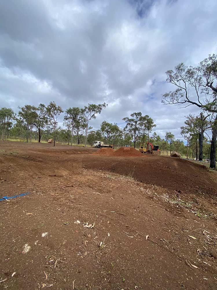 A Dirt Road With Trees in the Background and a Cloudy Sky — Blue Gum Earthworks in Atherton, QLD