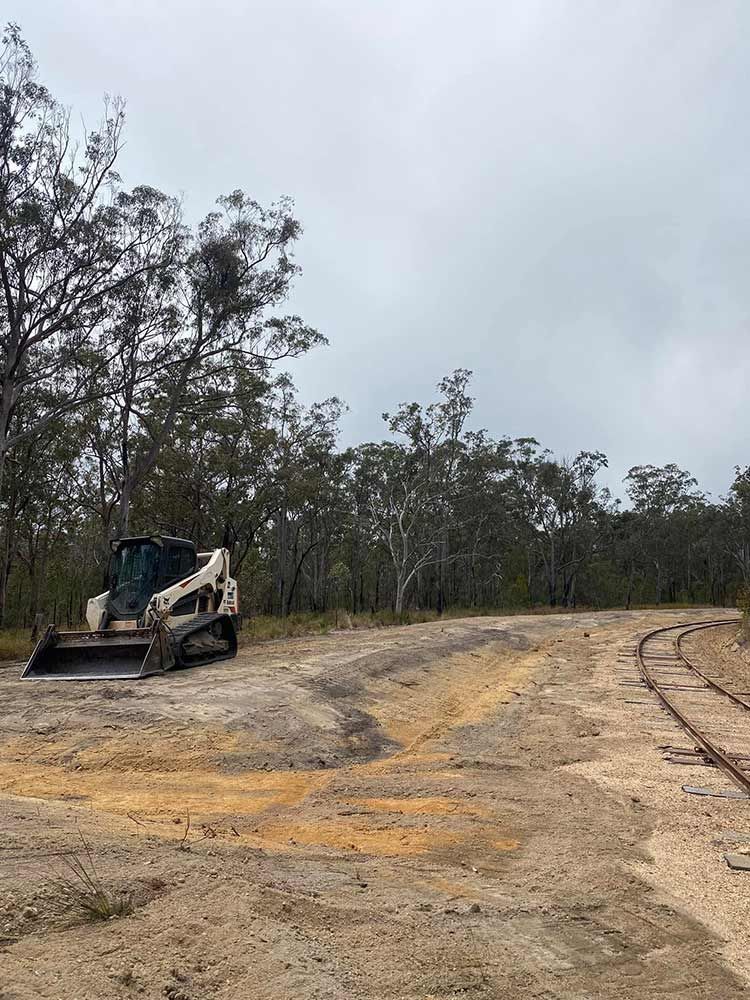 A Bulldozer is Parked on the Side of a Dirt Road — Blue Gum Earthworks in Atherton, QLD