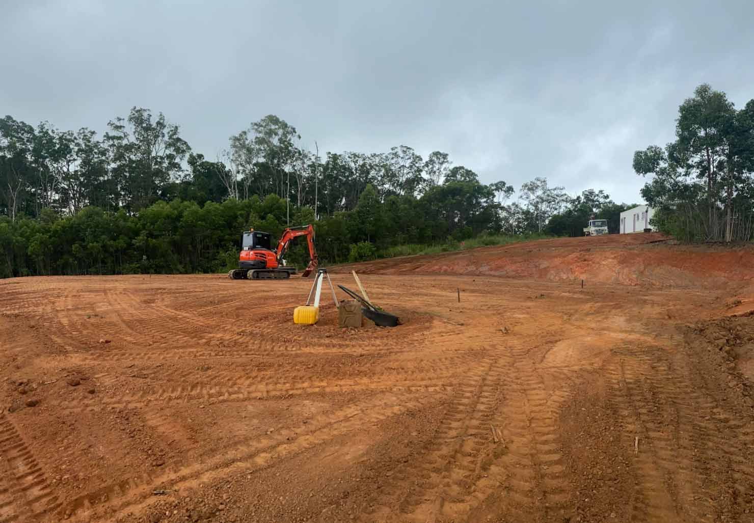 A Small Excavator is Sitting in the Middle of a Dirt Field — Blue Gum Earthworks in Atherton, QLD