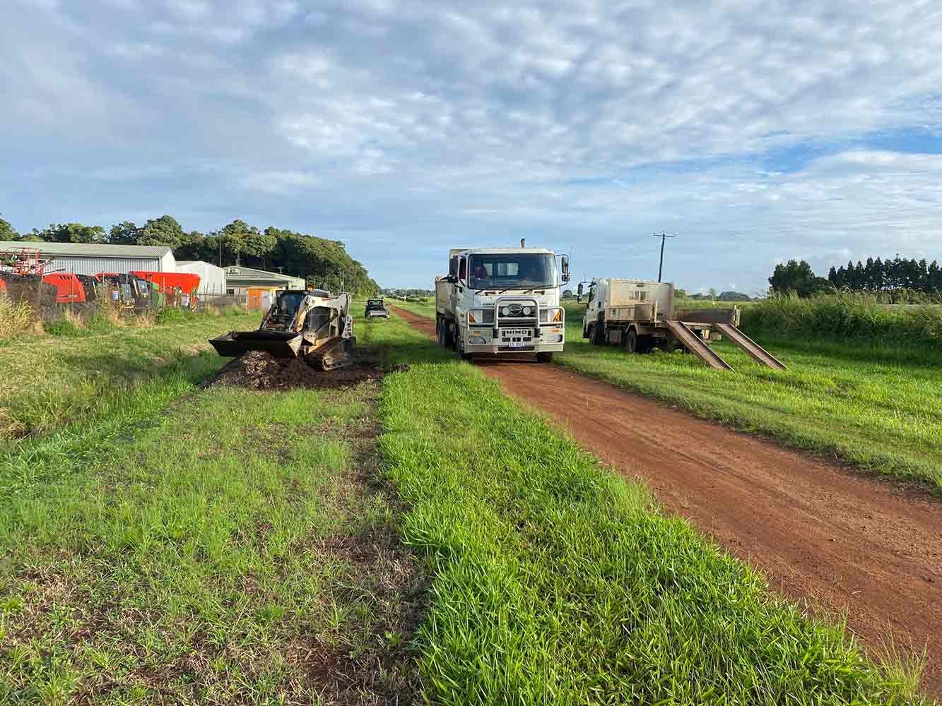 Two Trucks Are Parked on the Side of a Dirt Road in a Field — Blue Gum Earthworks in Atherton, QLD