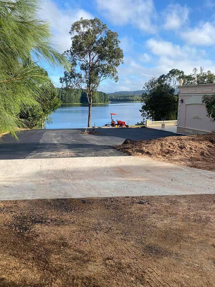 A Road Leading to a Lake With a House in the Background — Blue Gum Earthworks in Atherton, QLD
