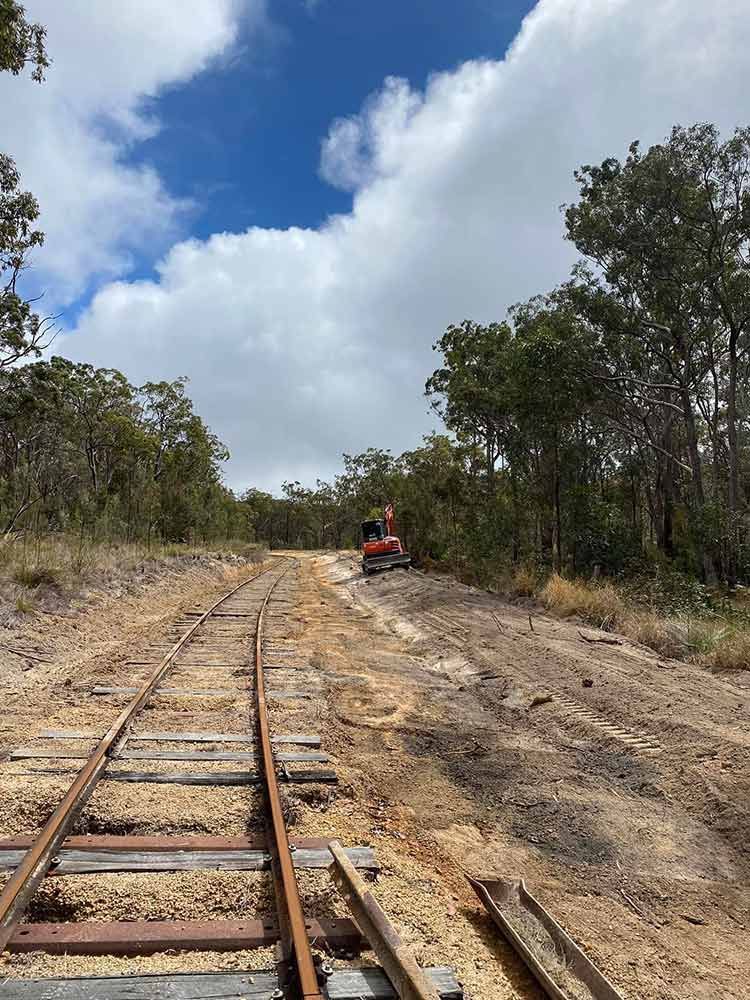 A Train Track in the Middle of a Dirt Field With Trees in the Background — Blue Gum Earthworks in Atherton, QLD