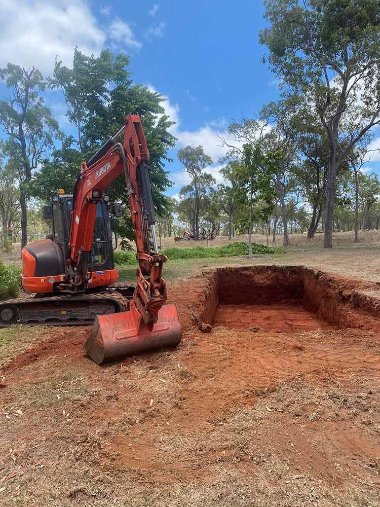 An Excavator is Digging a Hole in the Dirt in a Field — Blue Gum Earthworks in Atherton, QLD