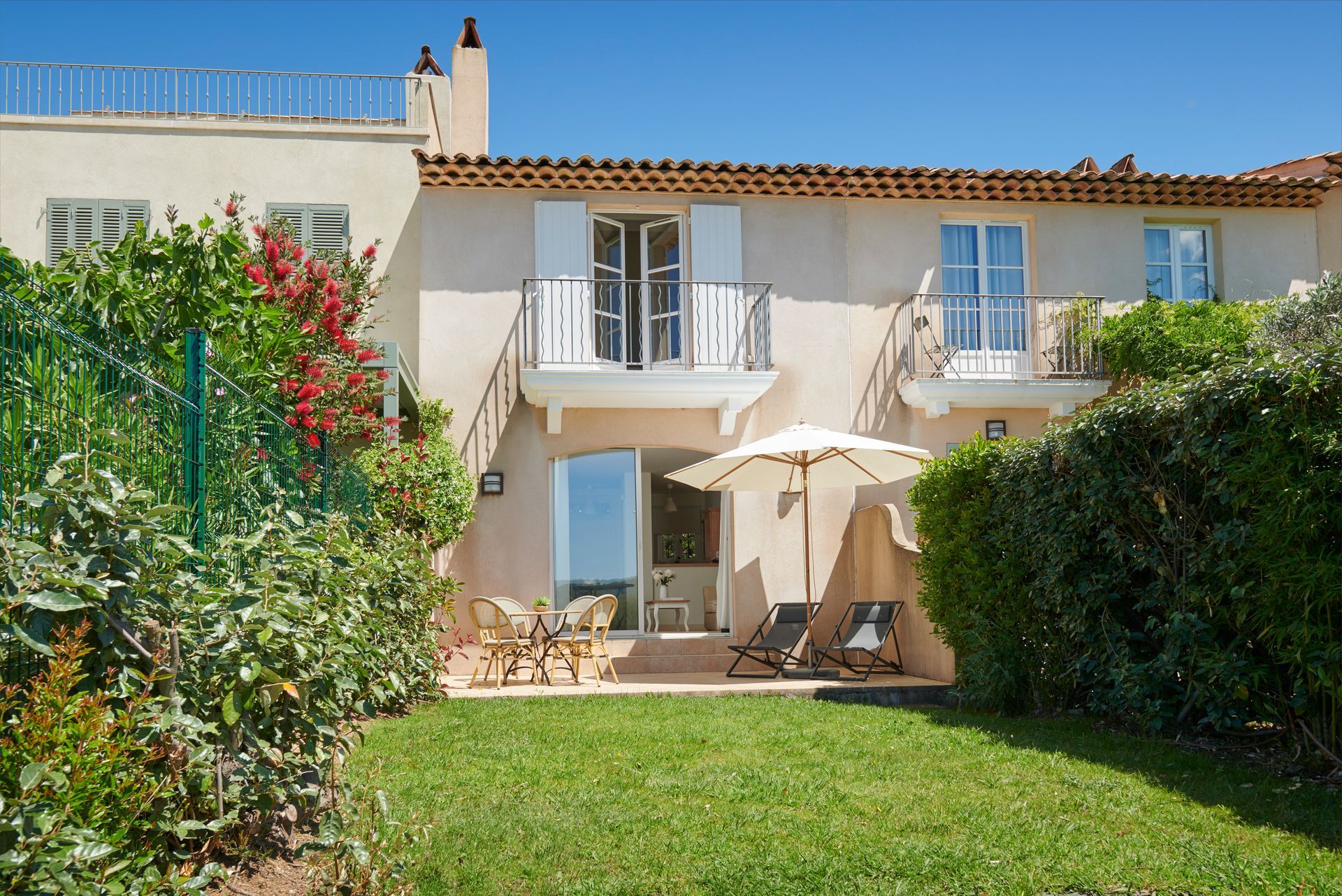 A house with a balcony and umbrellas in front of it